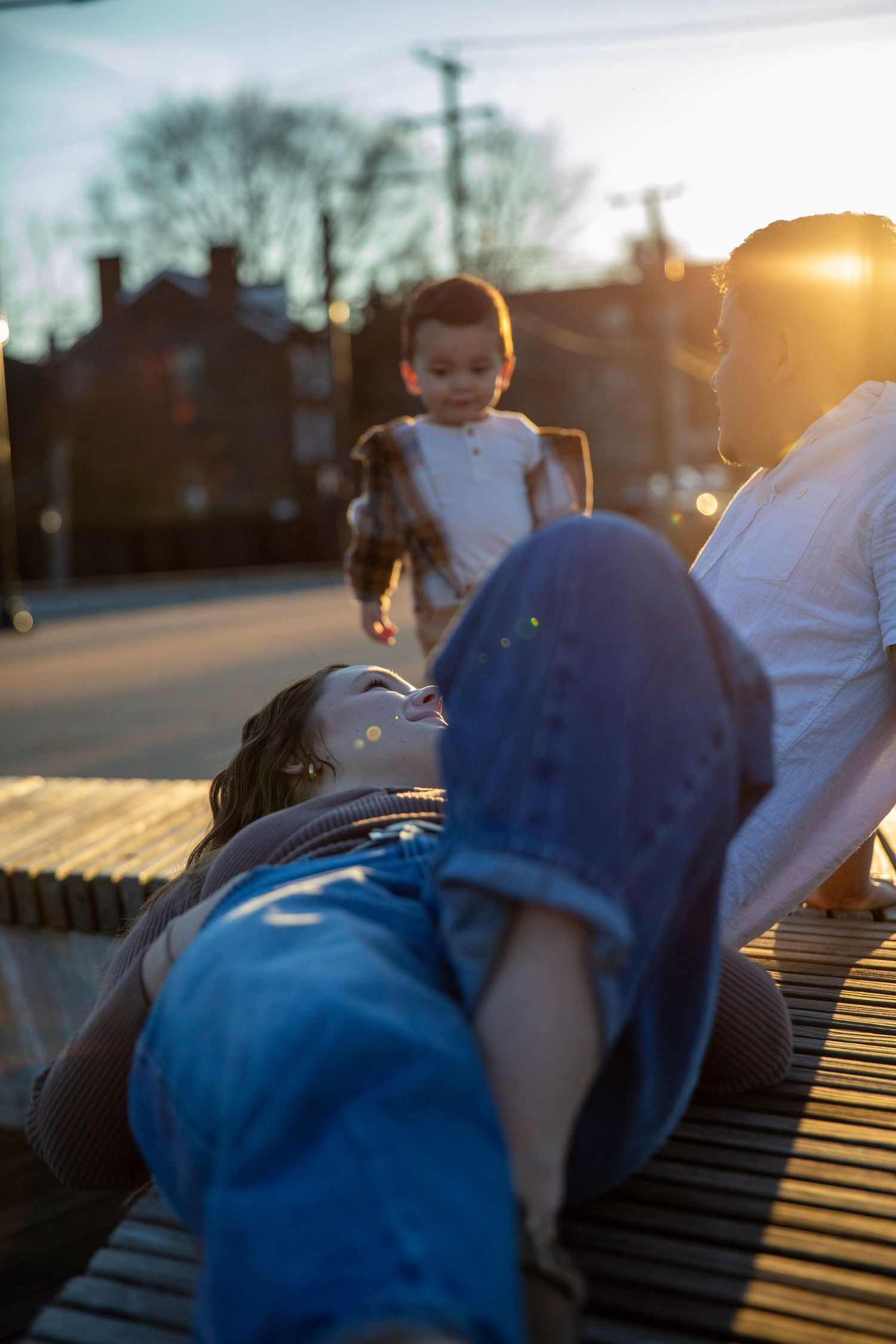 Toddler boy runs toward mom and dad  in the sunset