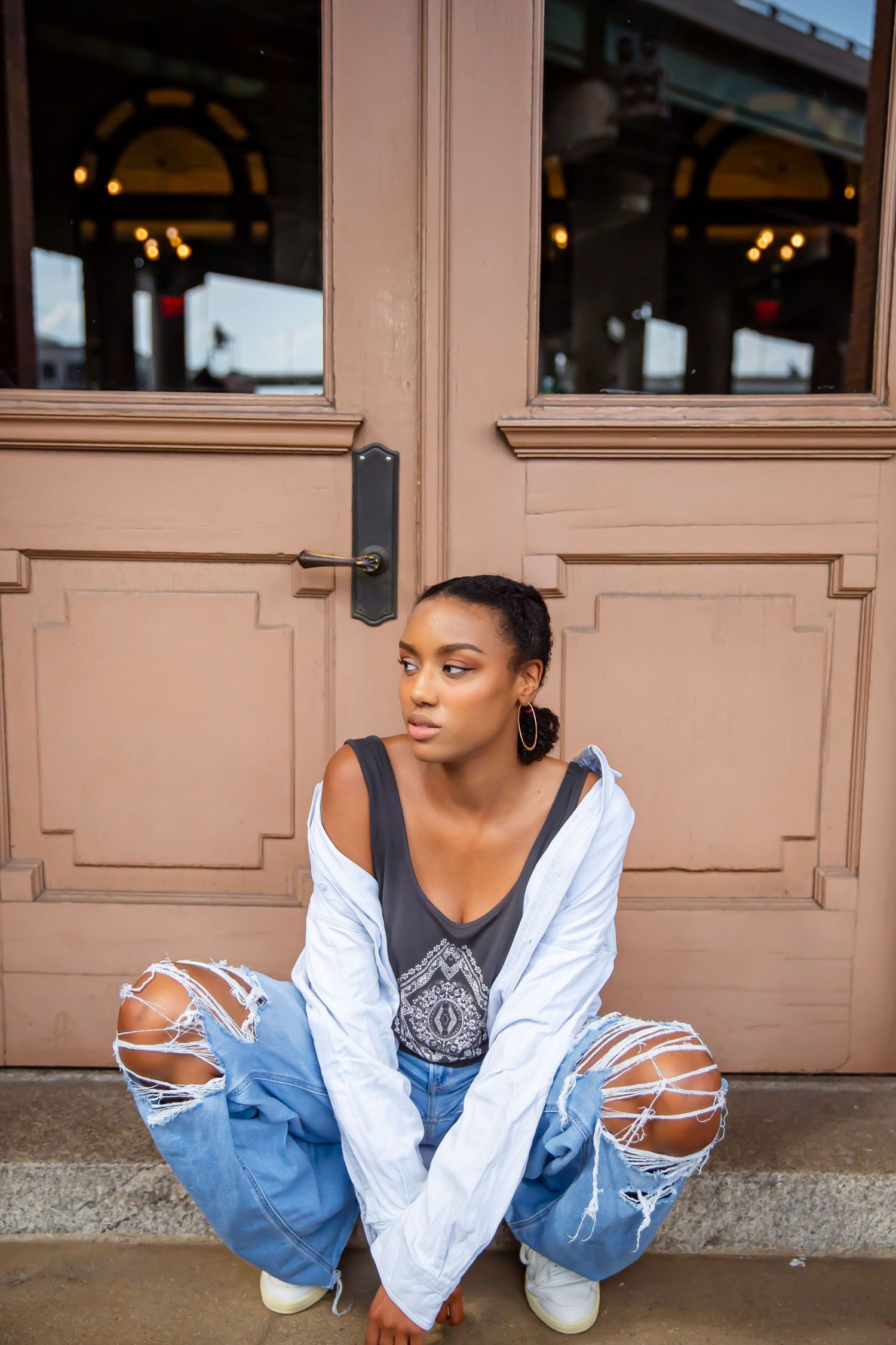 Female model in sitting position in front of a doorway.