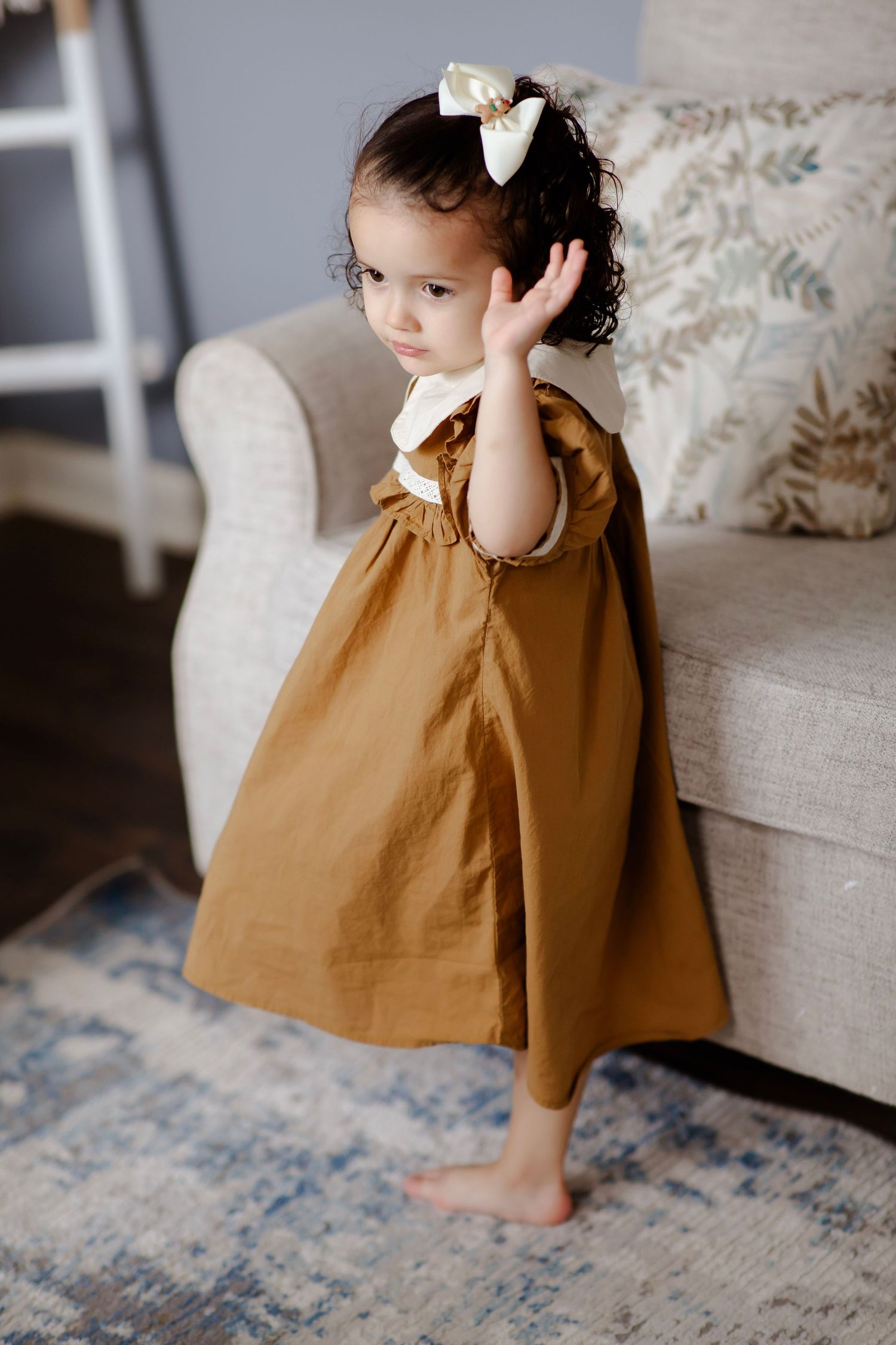 Little girl in a solitary moment leaning against the couch