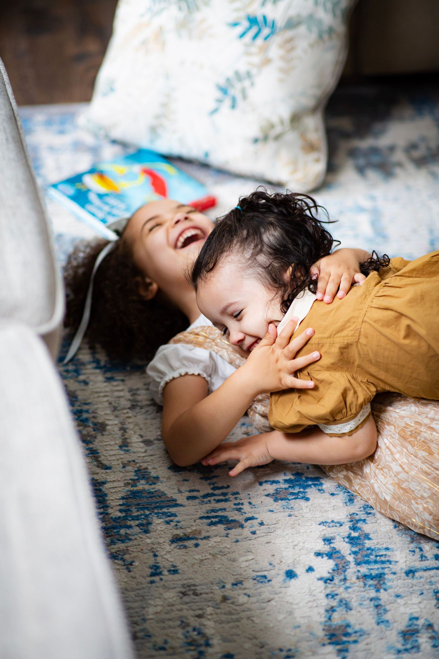 Two young sisters fallen on the floor in laughter