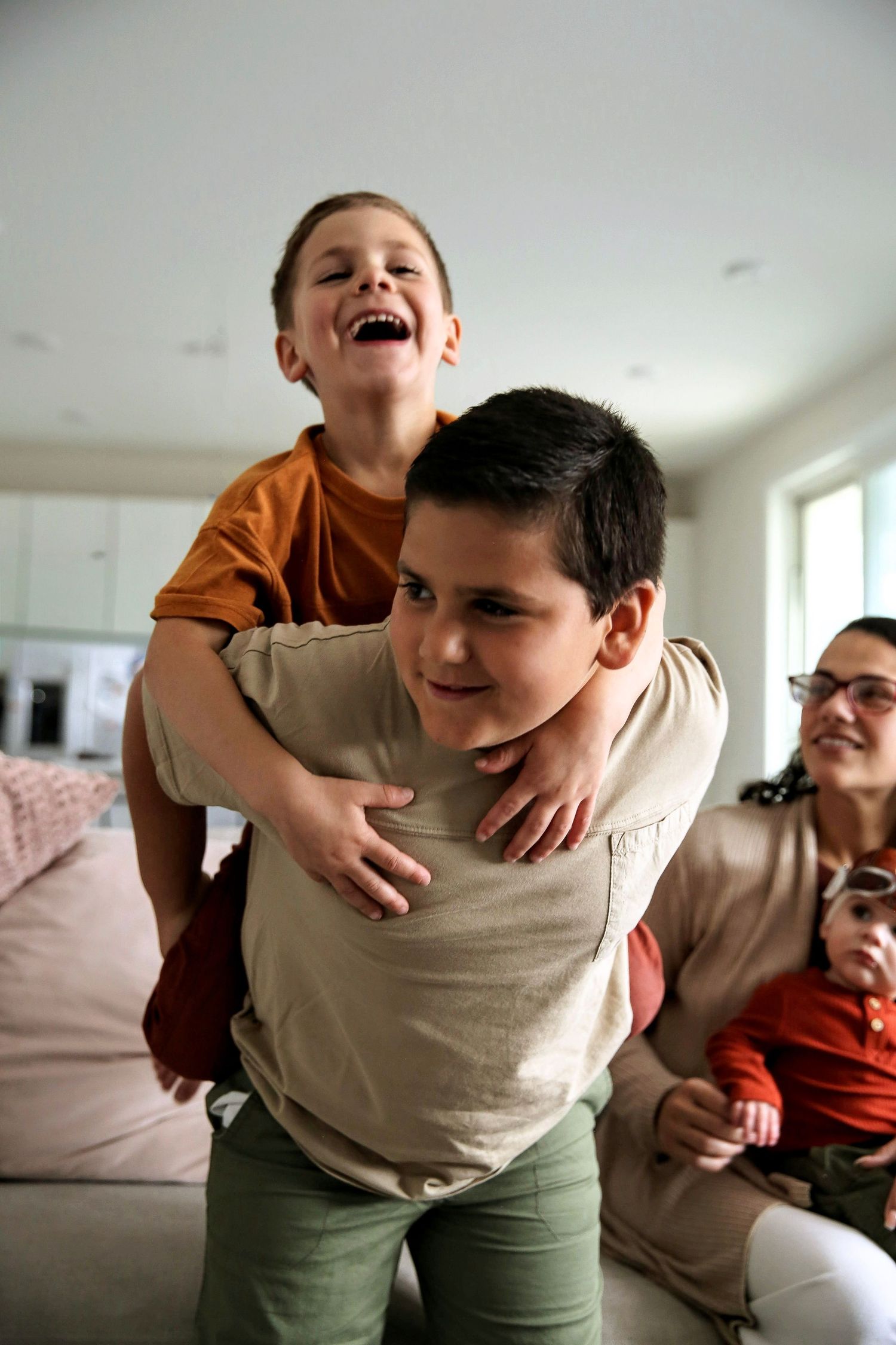 Brothers laughing while little brother gets a piggy back ride on big brother's back.