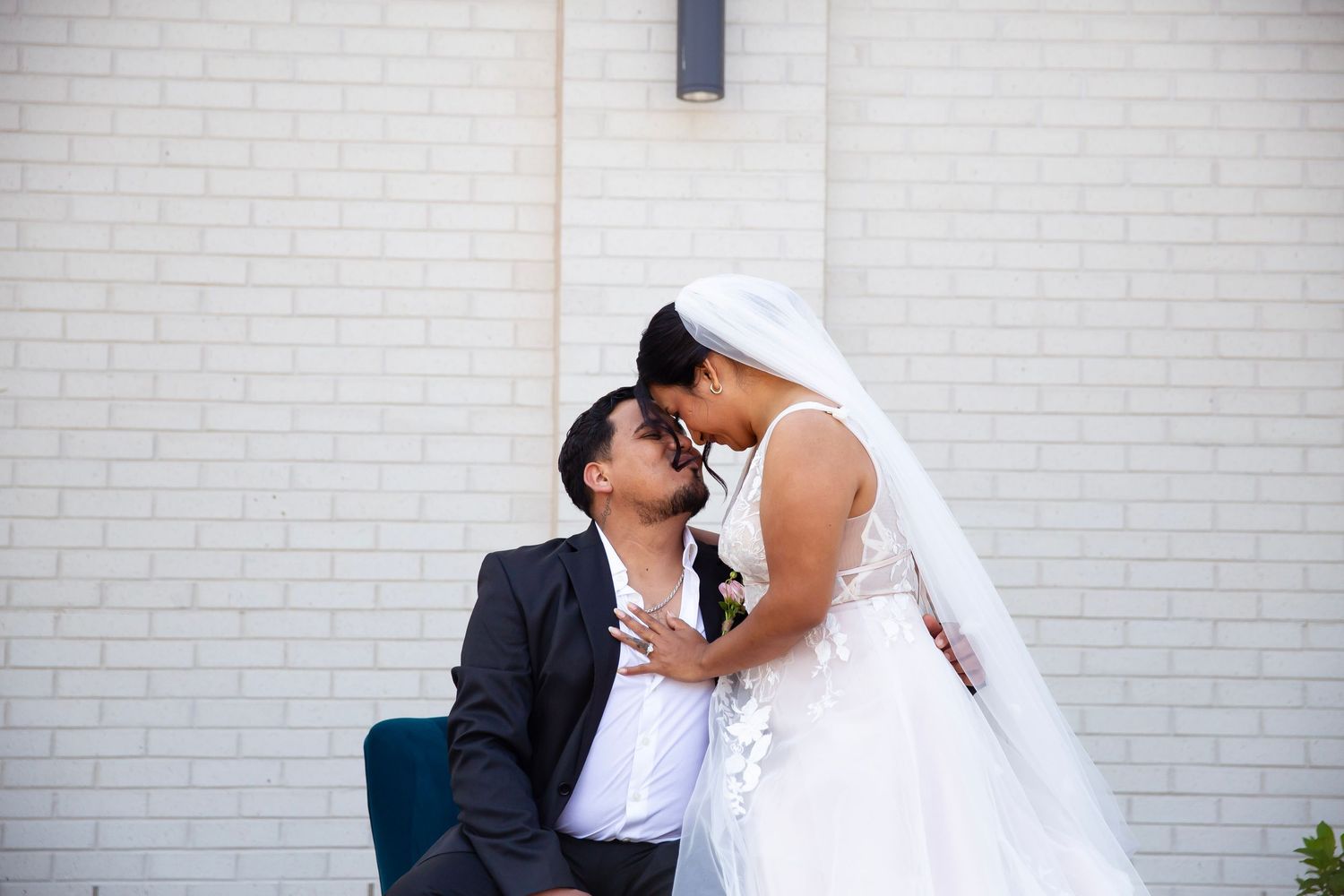 Wedding Scene with Bride and groom sharing a kiss with the bride on grooms knee