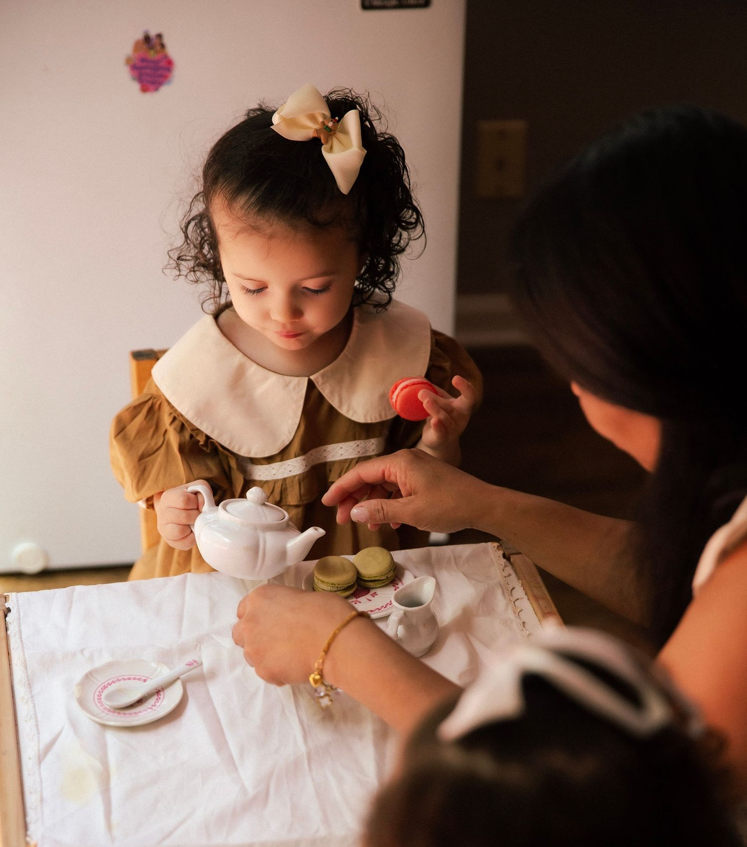 Mom helping toddler girl at a tea party