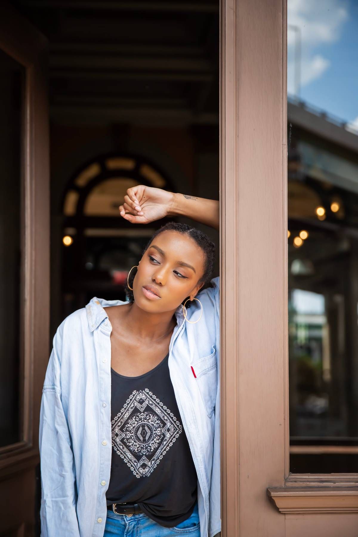 Female model leaning against door frame and looking outward