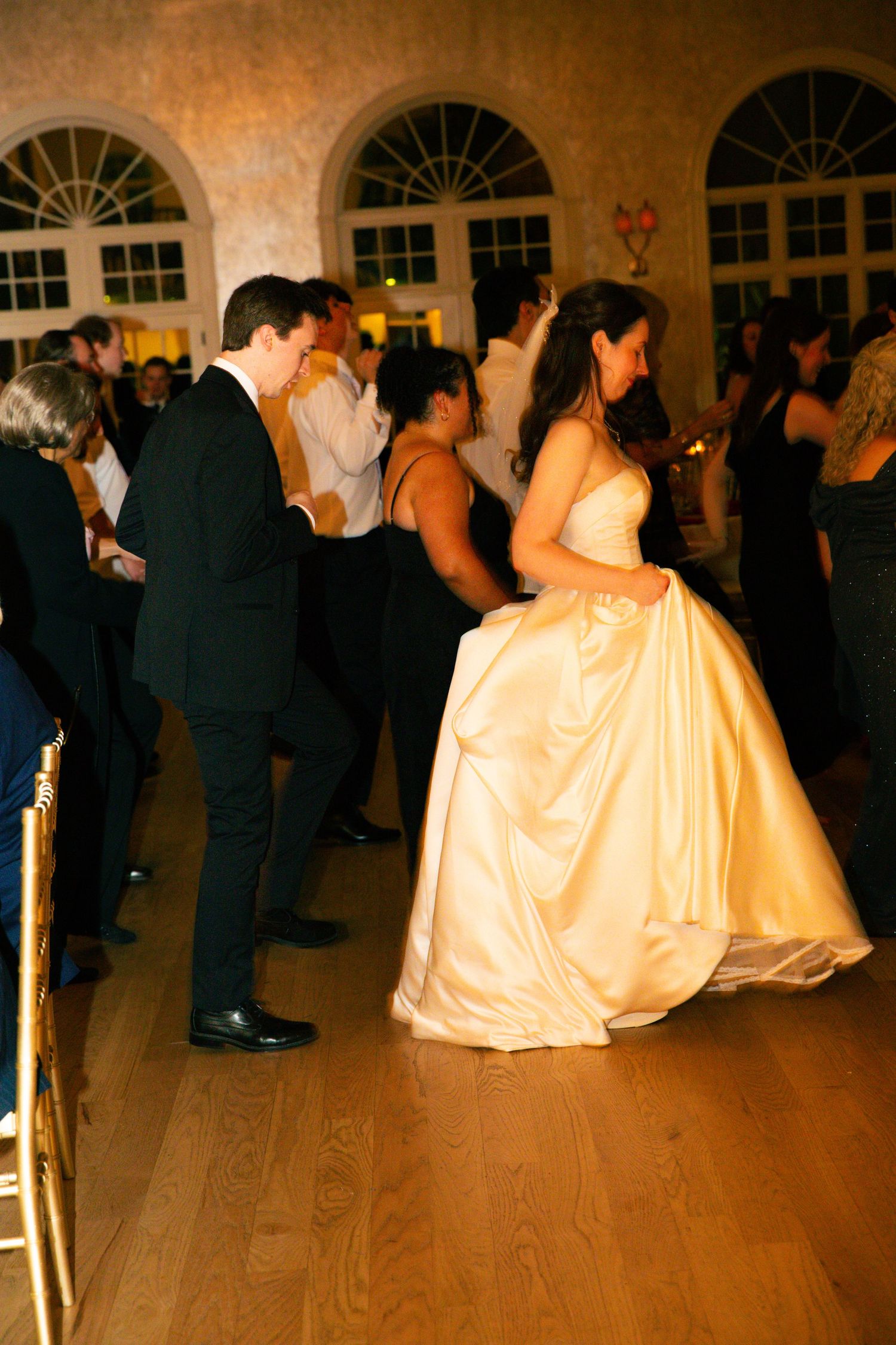 Bride in ivory ball gown and groom in black tuxedo dancing together at elegant wedding reception.
