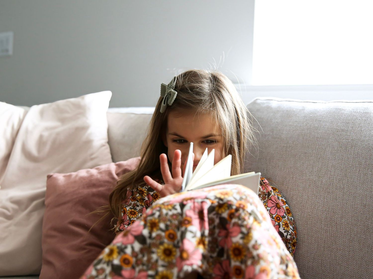 Young daughter reading book on couch.