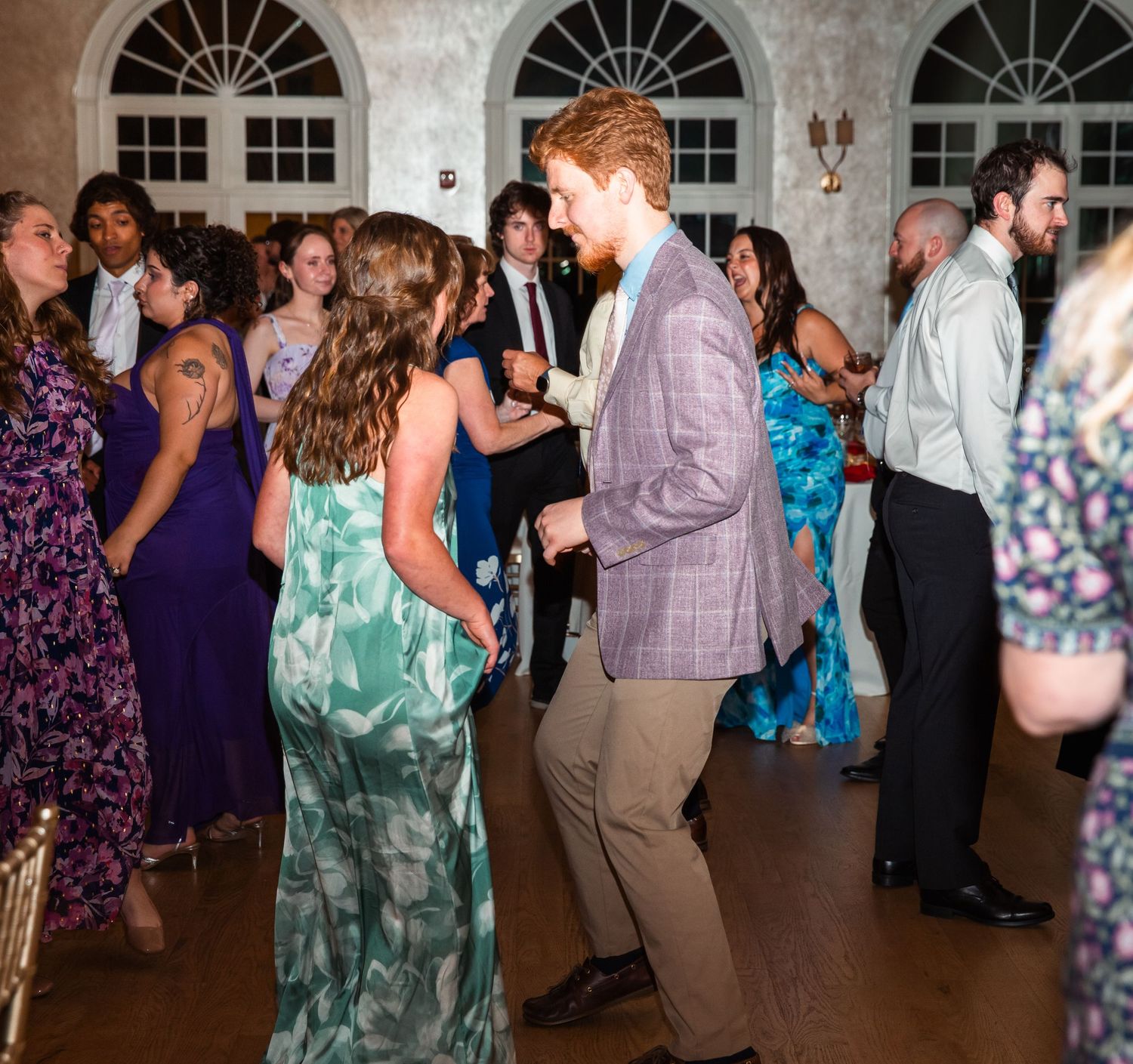 Wedding guests dance energetically on the dance floor at reception.