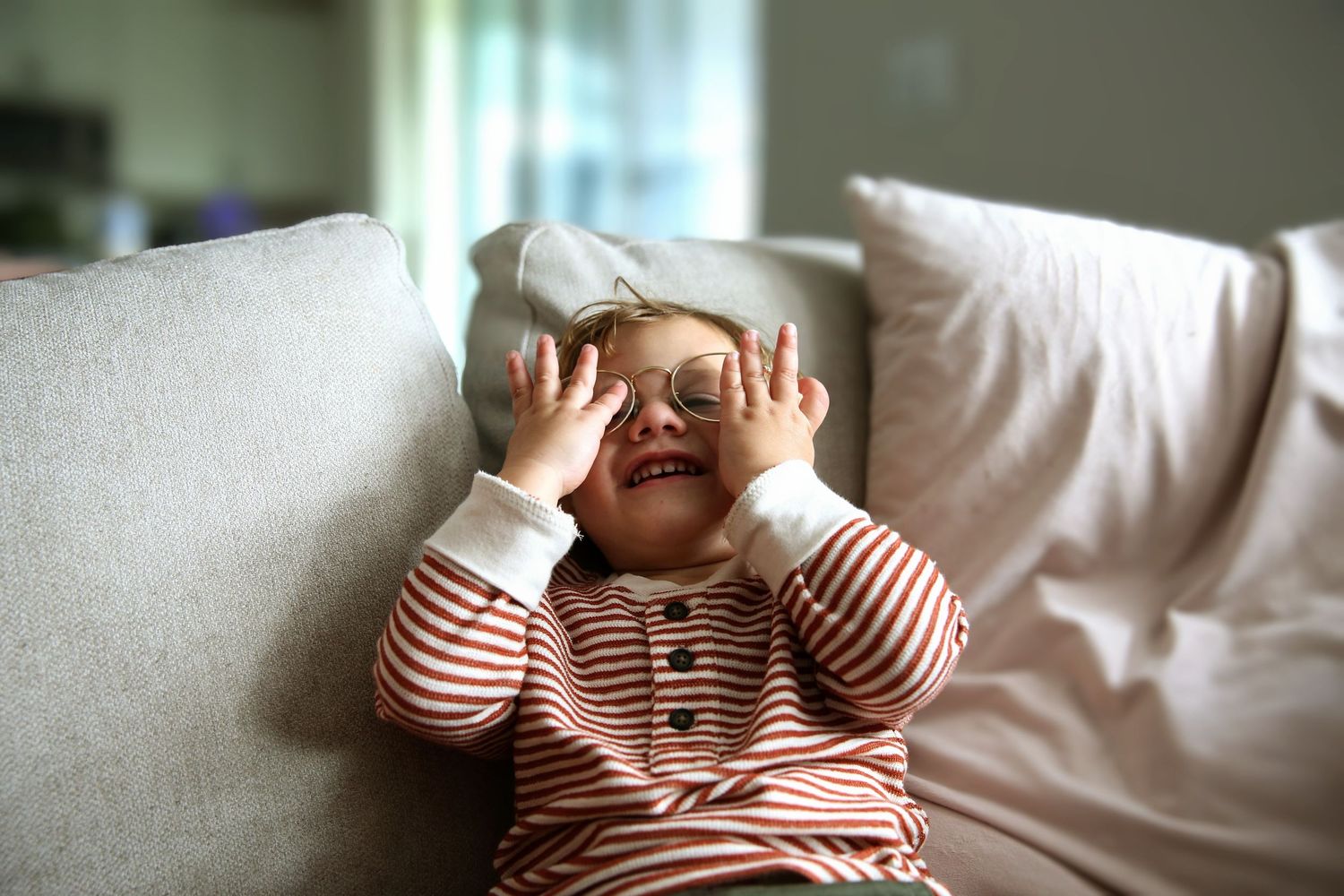 Toddler boy laughing  while playing with mom's eyeglasses.