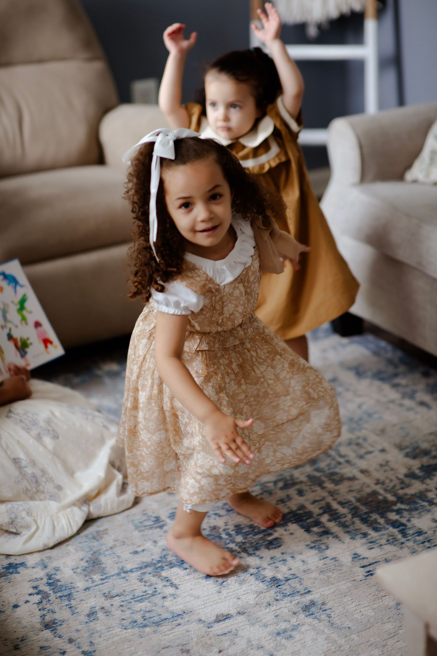 Two little sisters twirling in their dresses.