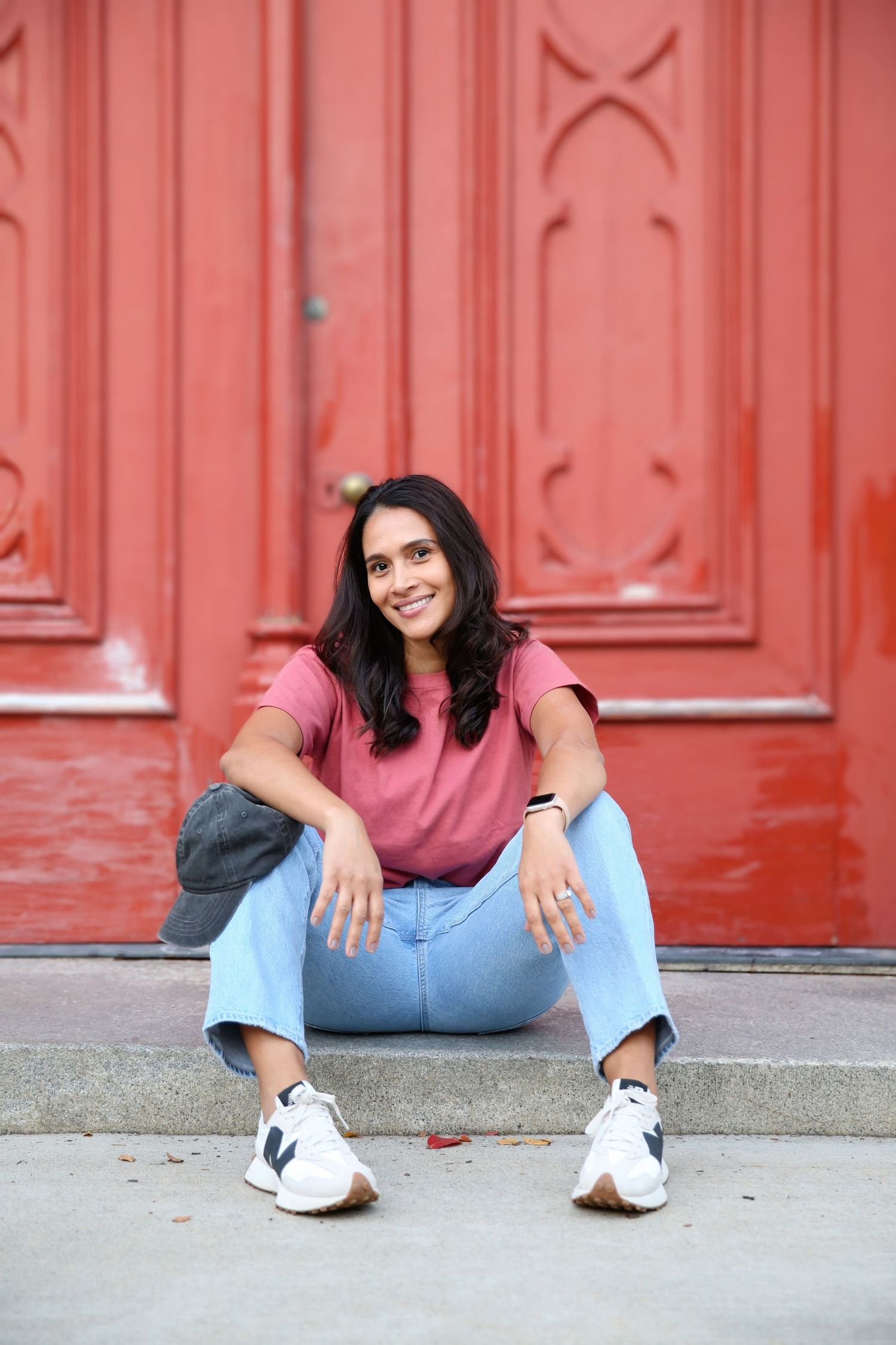 Female model sitting on a step in front of a red door