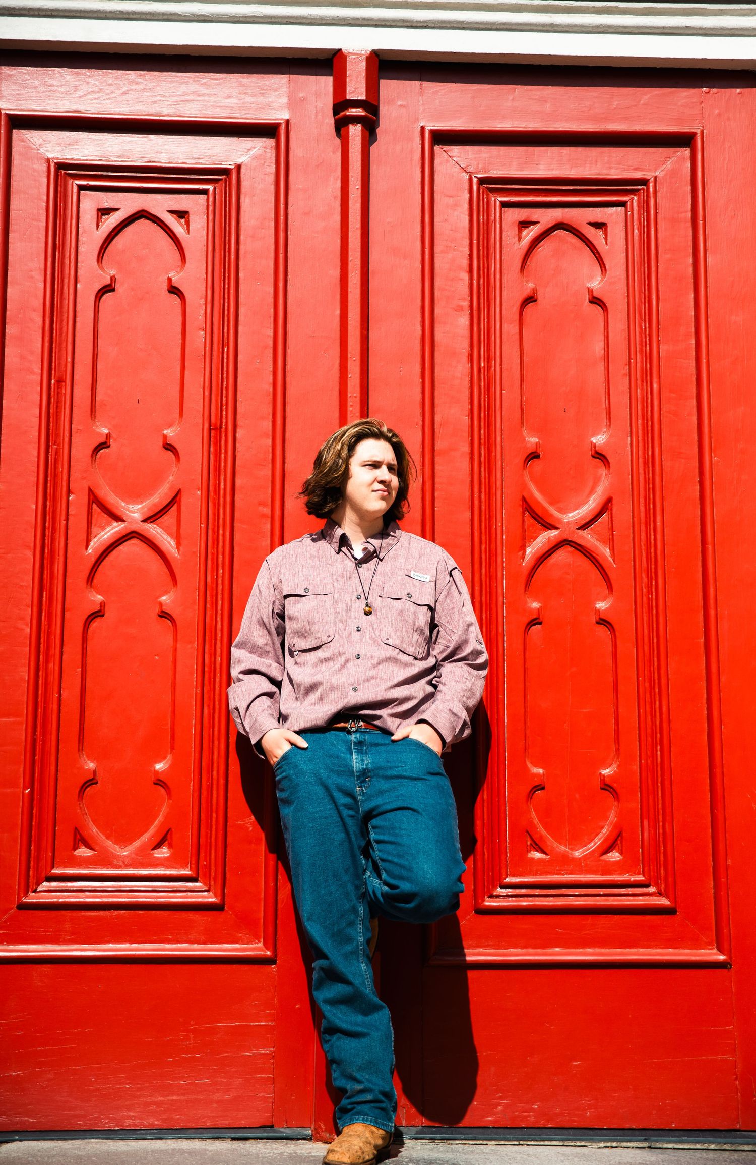 Highschool senior boy leans against red door