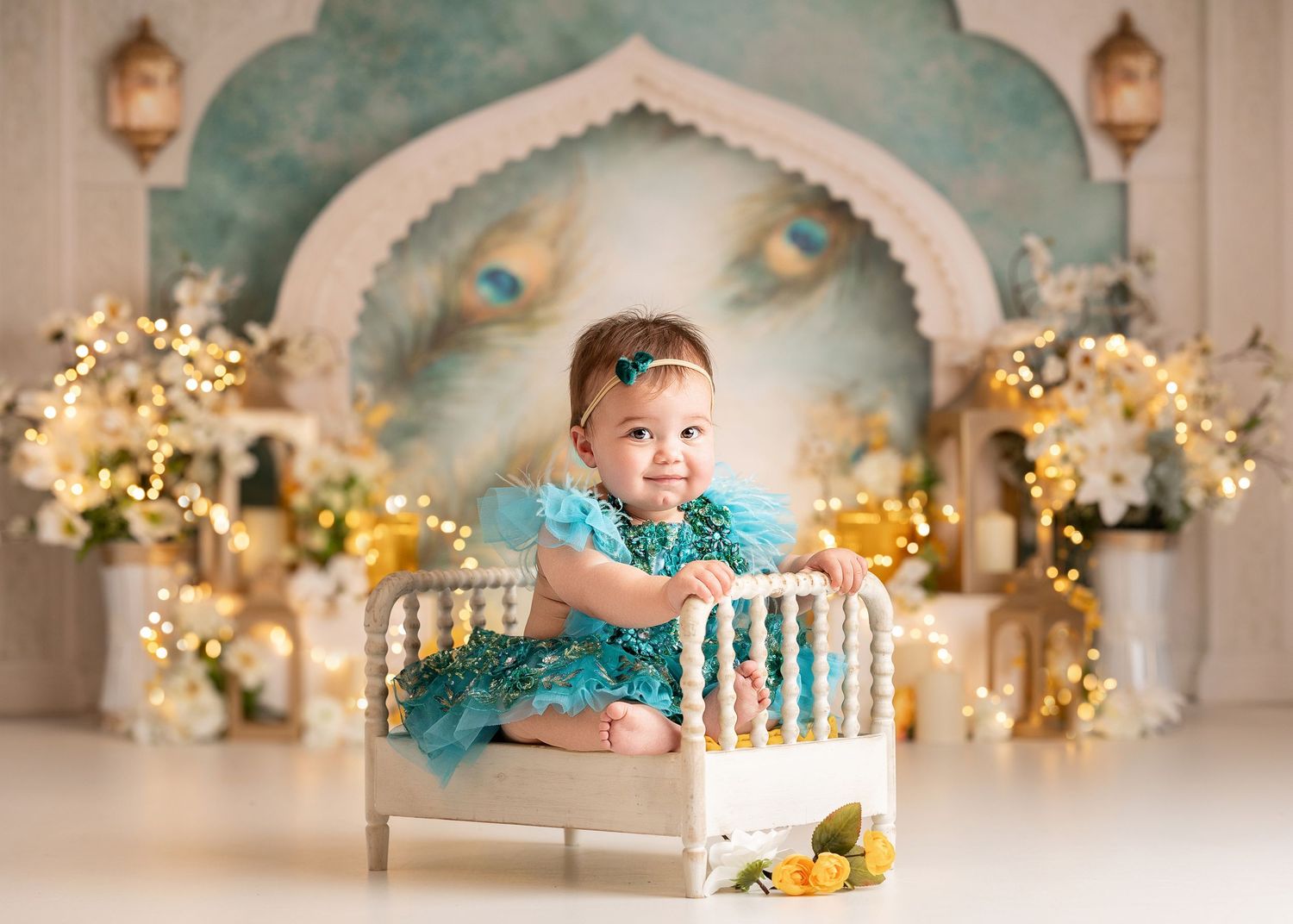 Bridgerton Theme, Baby girl in teal ruffle dress sits in miniature white bed with fairy lights and floral backdrop for first birthday photo.