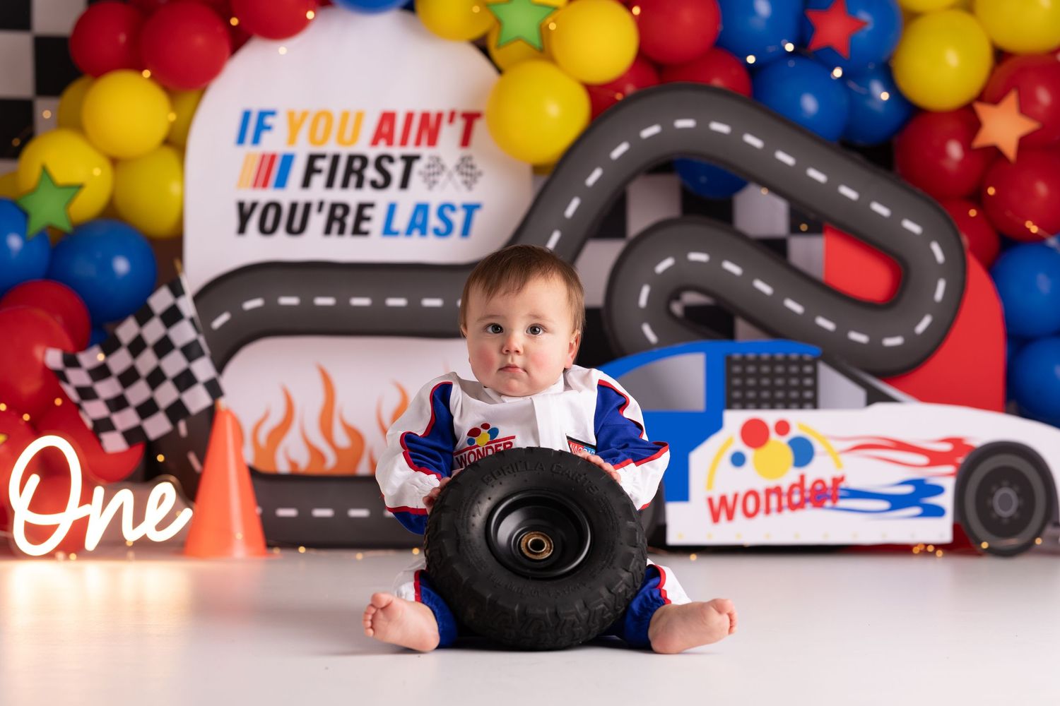 Baby's first birthday cake smash with racing theme,  Ricky Bobby, colorful balloons, and race car decorations, if you ain't first your last.