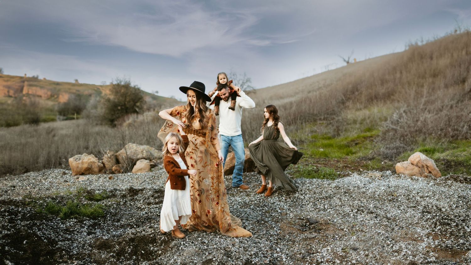 Family of five posing playfully around an old tree in a scenic outdoor landscape with rolling hills, Pena Adobe, Vacaville, CA.