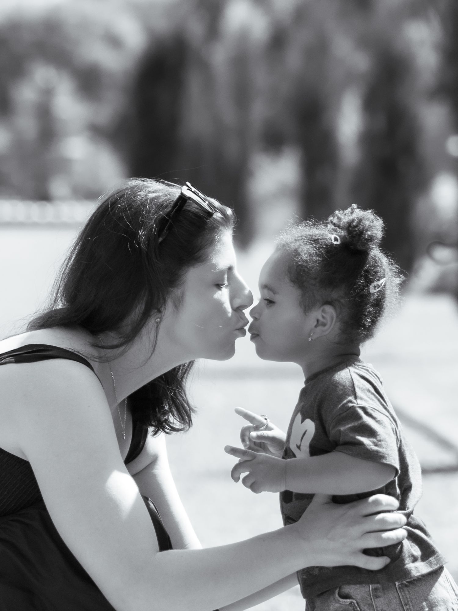 Black and white photo of a mother sharing a tender nose-to-nose moment with her young curly-haired toddler.