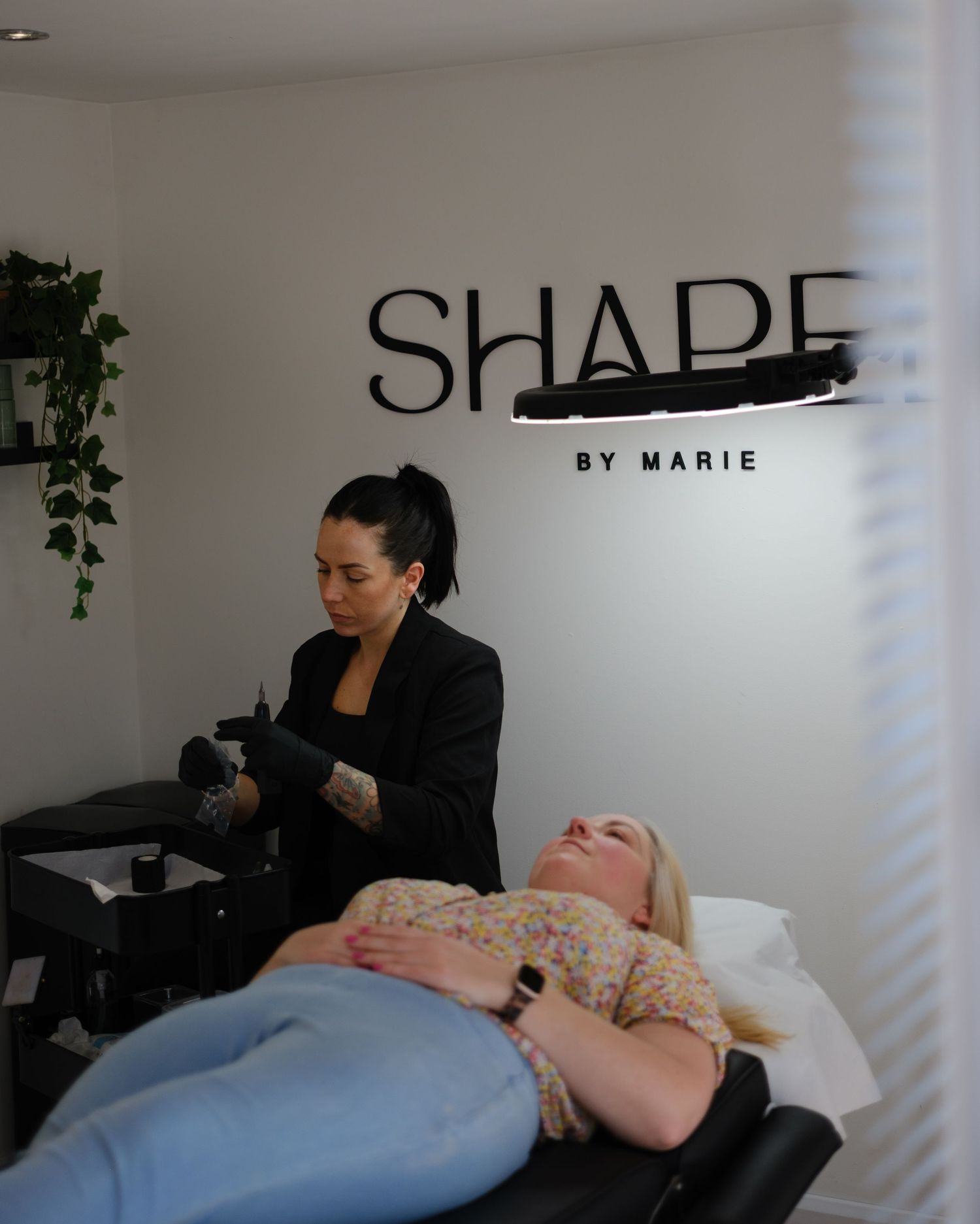 Brow artist performing eyebrow treatment on client at Shape by Marie beauty studio.