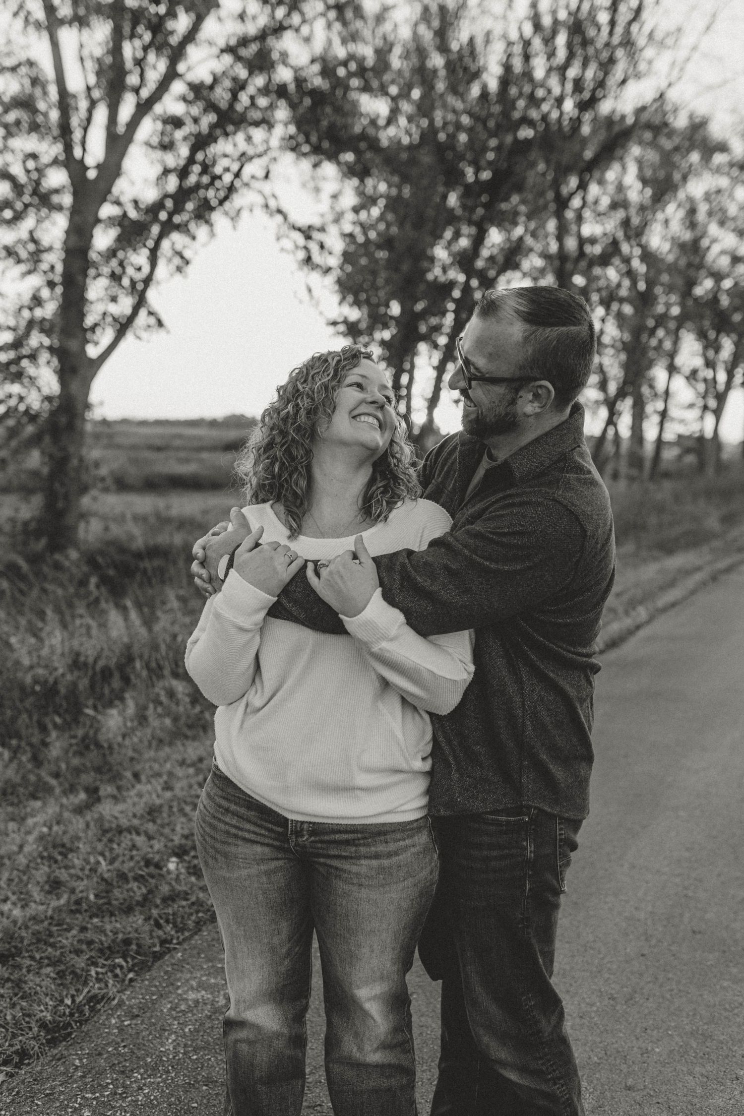 Couple embracing and smiling at each other on rural road in black and white photo.
