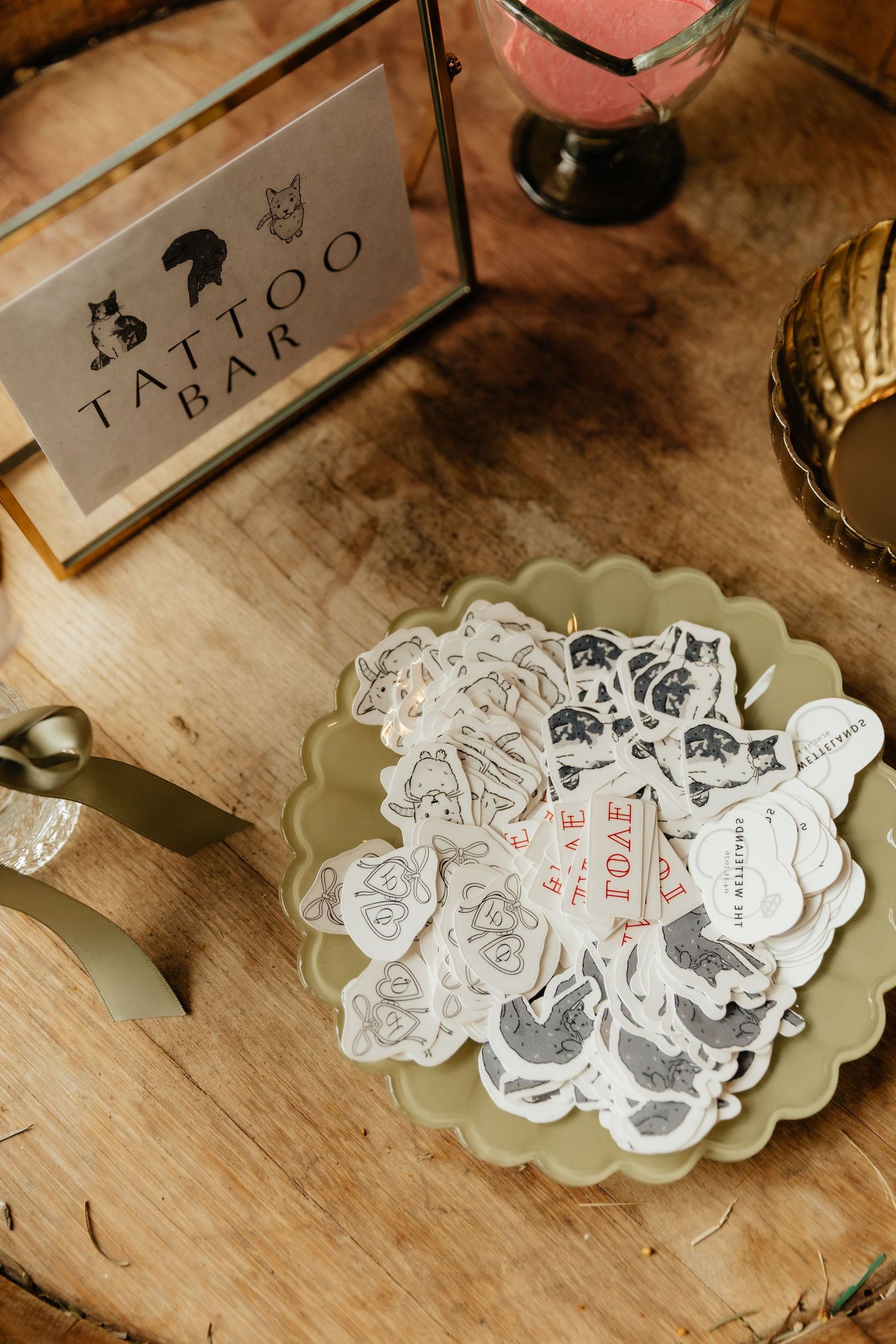 Wedding tattoo bar display with temporary tattoos on a green scalloped plate beside a decorative sign on wood table.