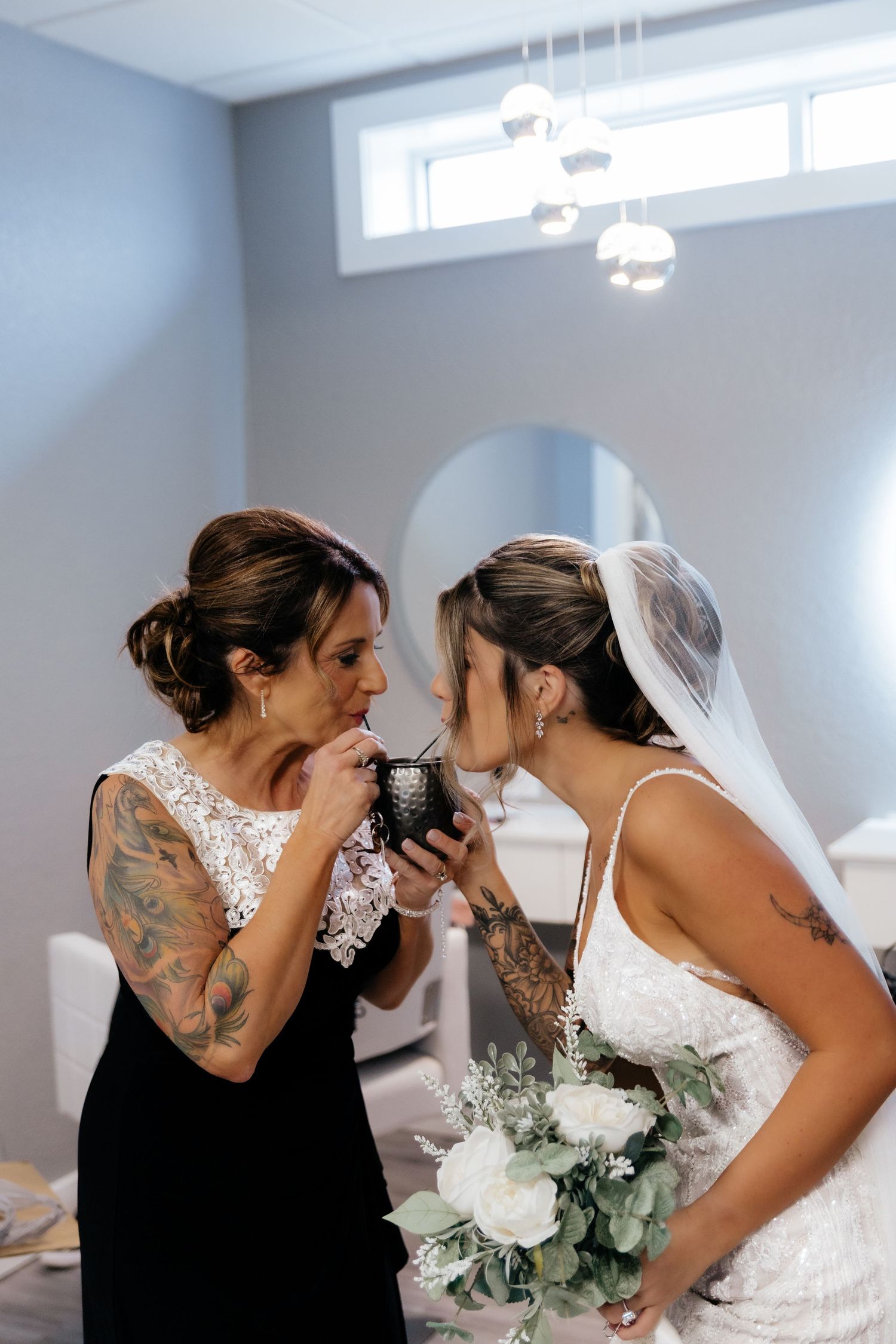Emotional bride holding white bouquet sharing a tender moment with her mother before the wedding.