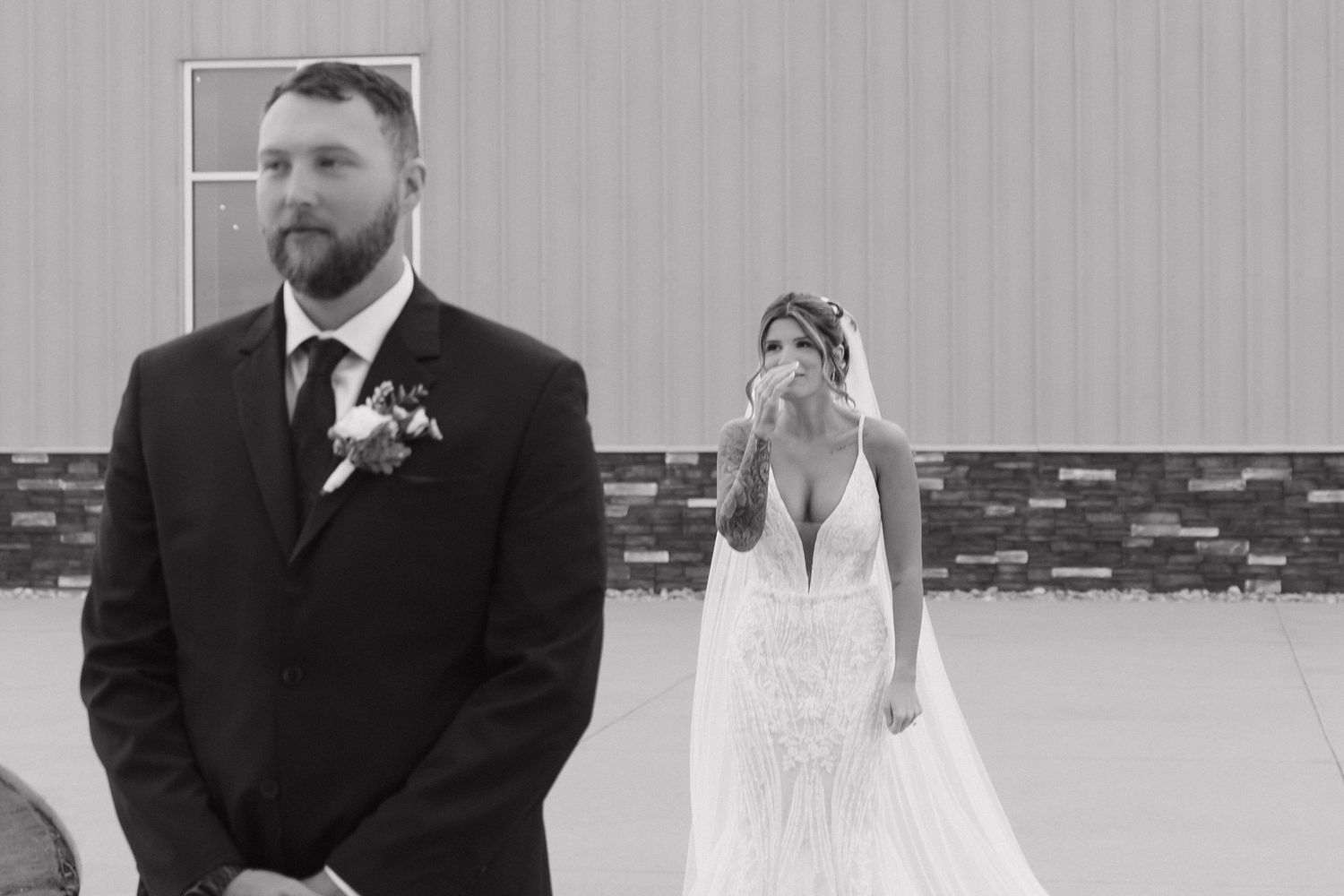 Black and white emotional first look moment as bride tearfully sees groom at outdoor wedding venue.