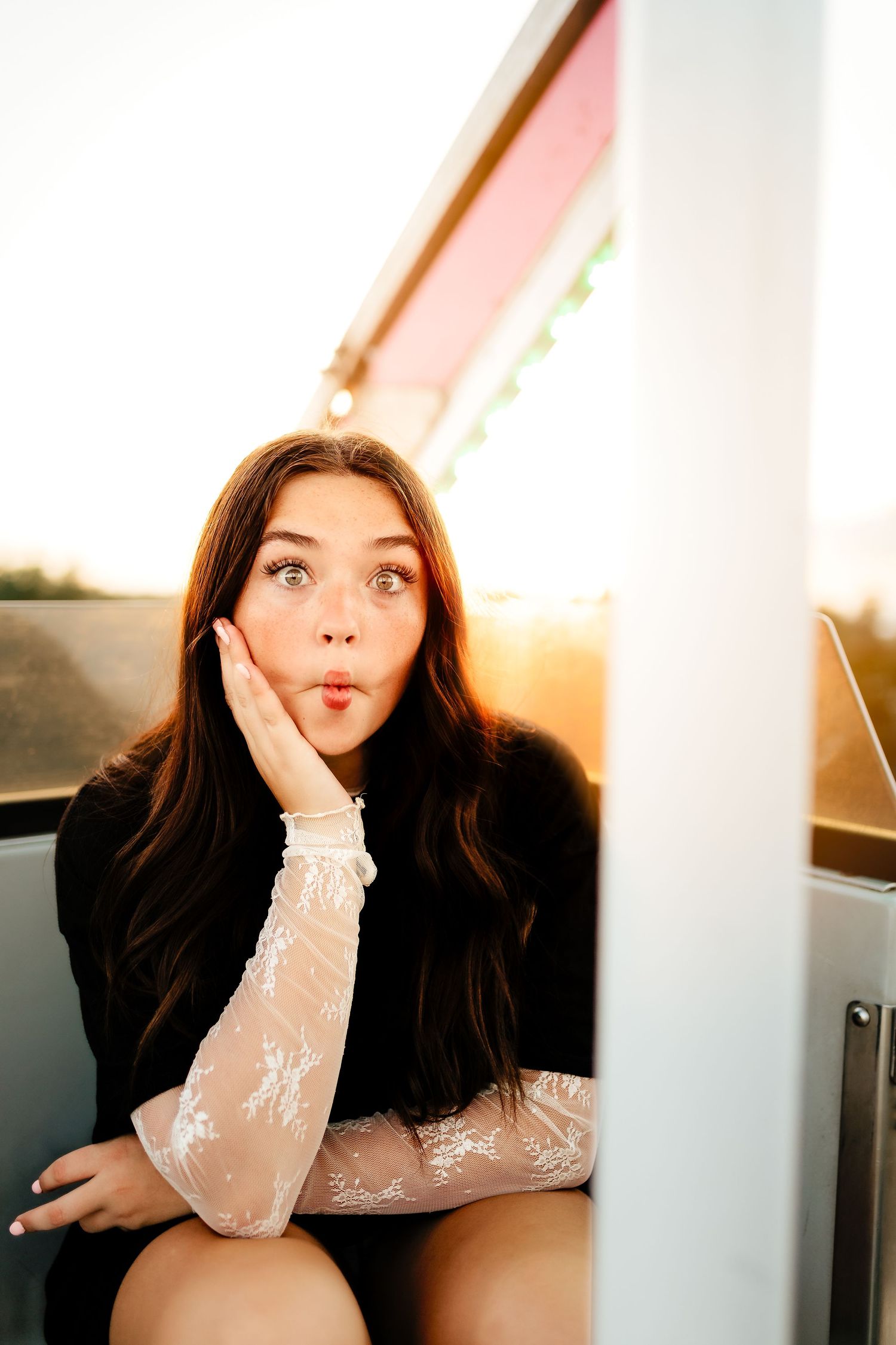 Young woman with long dark hair making a funny face while sitting in a carnival ride gondola.