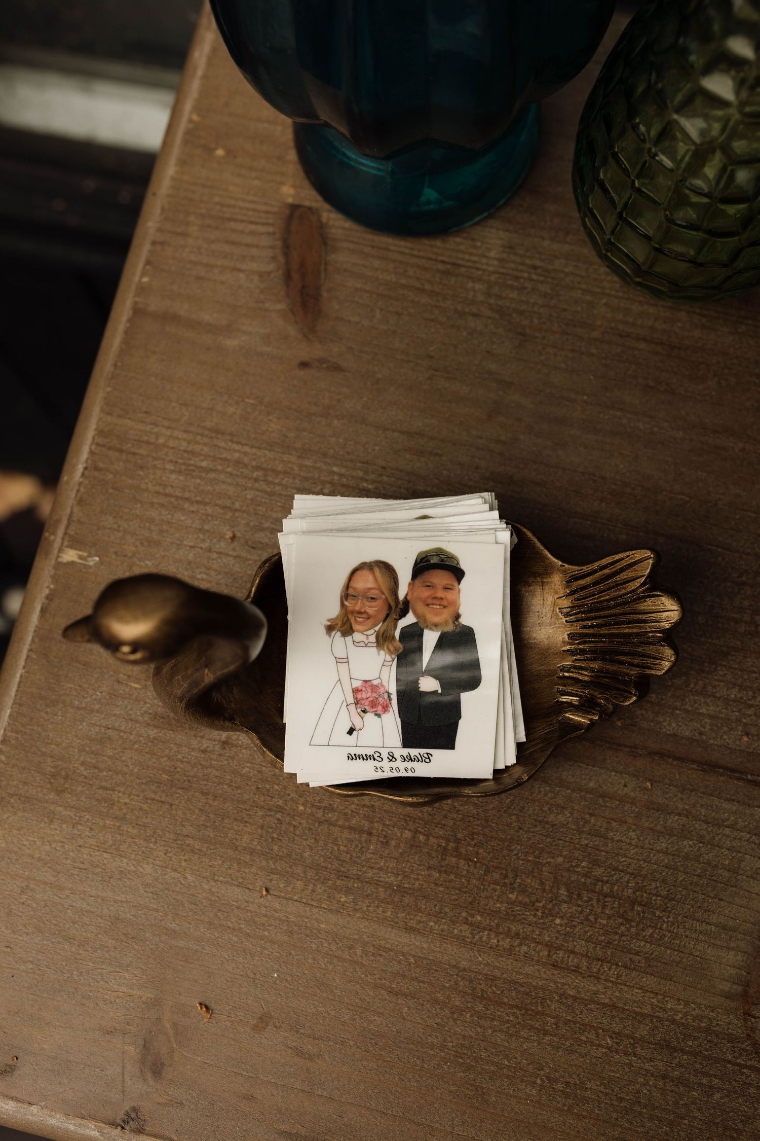 Stack of personalized wedding photo cards featuring the couple displayed in a decorative gold bird dish.