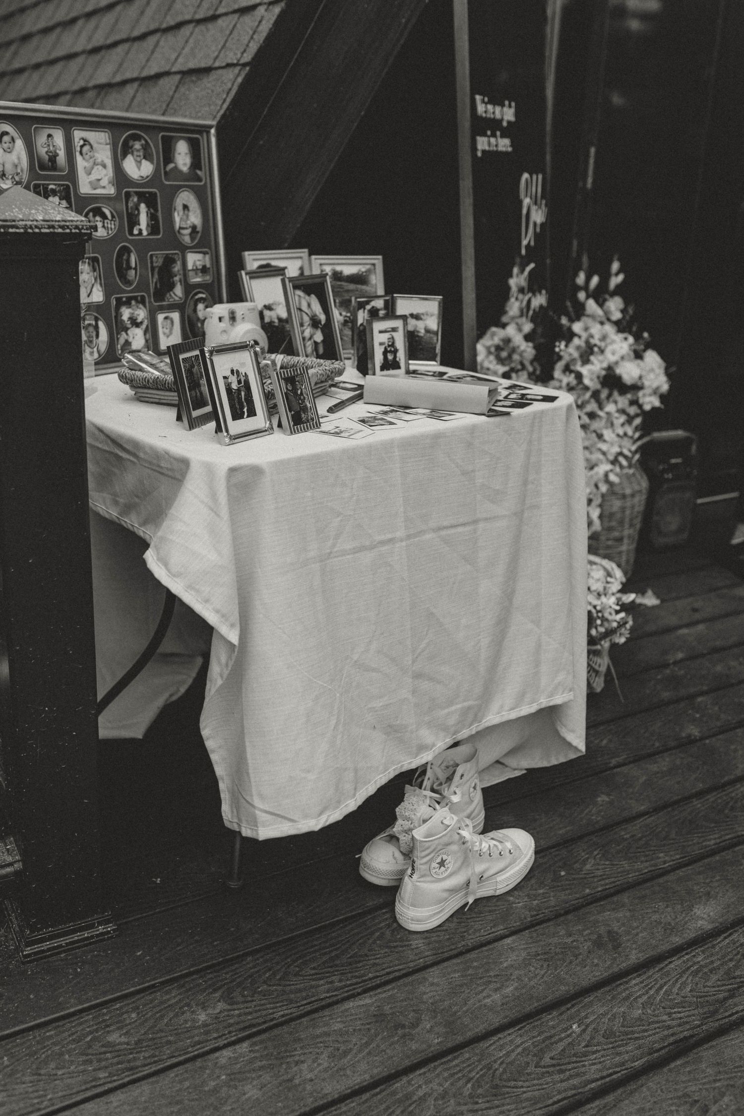 Black and white photo of a wedding memory table displaying framed family photos and flowers.