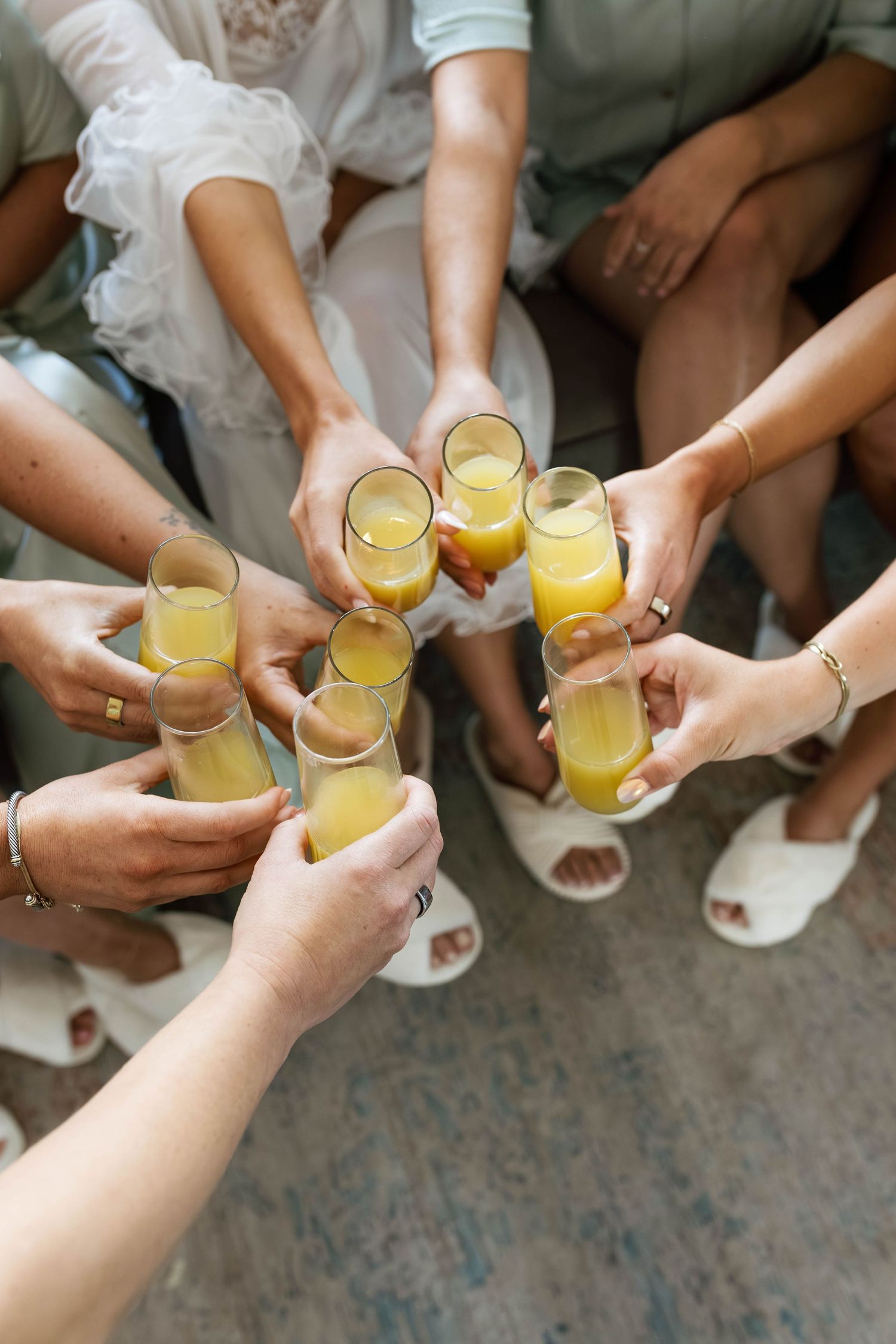 Group of women toasting with mimosas in champagne flutes during a bridal party celebration.