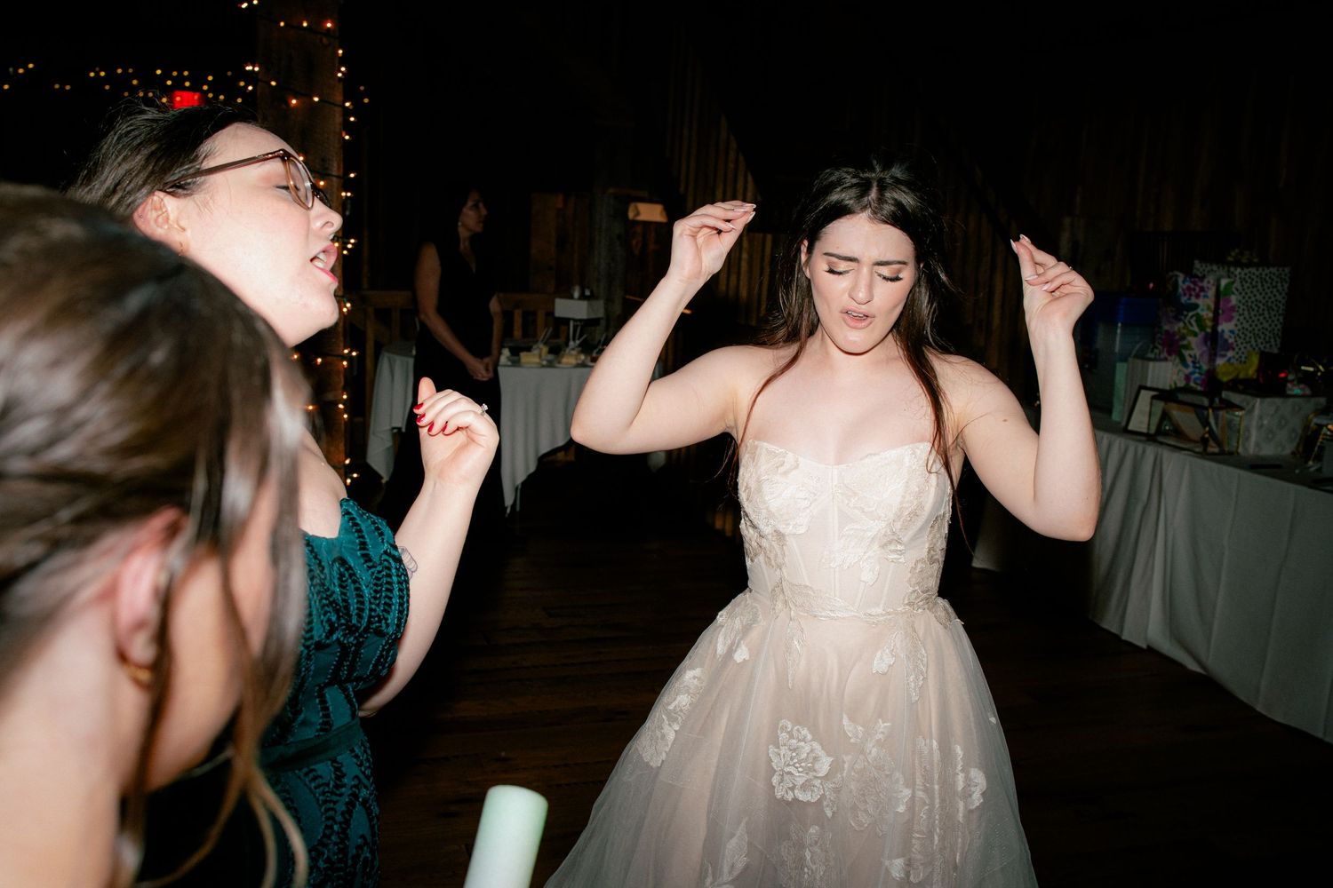 Bride in a tulle gown dances joyfully with guests at a lively wedding reception.