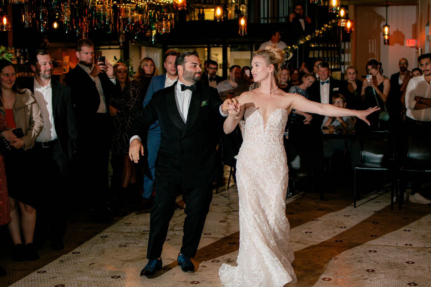 Bride in a beaded gown and groom in a tuxedo make a grand entrance at their elegant wedding reception.