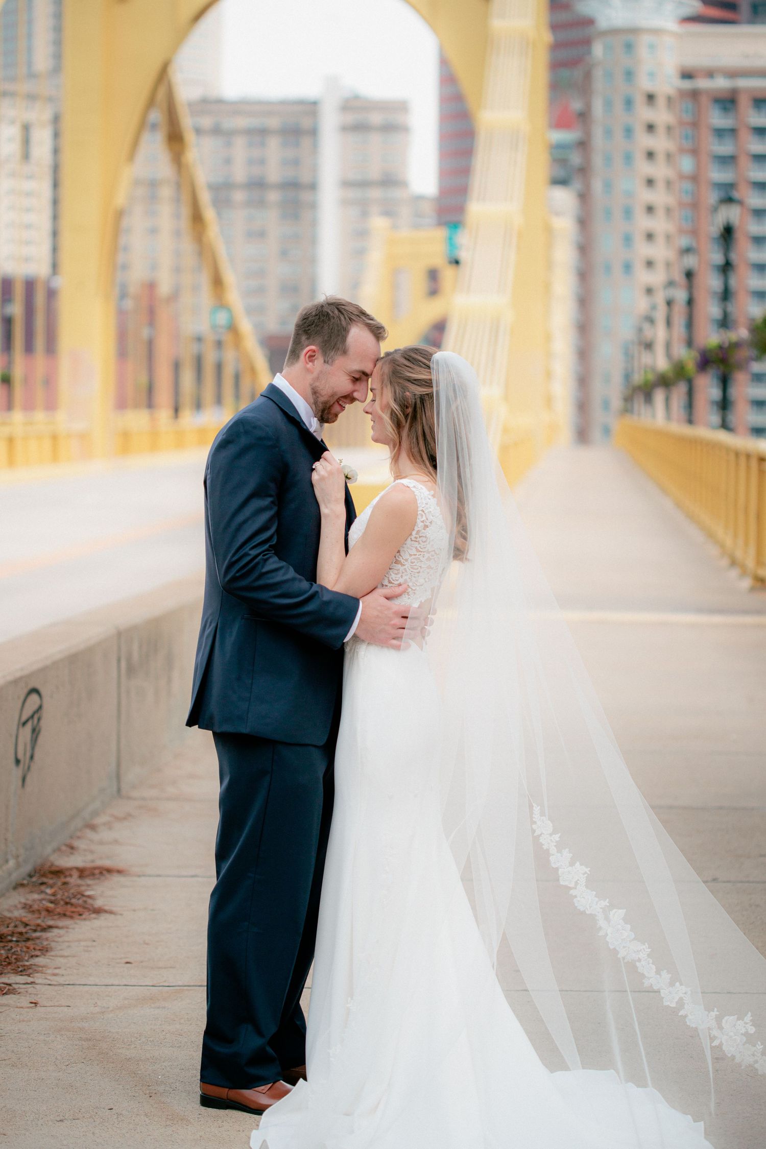 Wedding couple embracing and smiling on Pittsburgh's iconic yellow Andy Warhol Bridge.