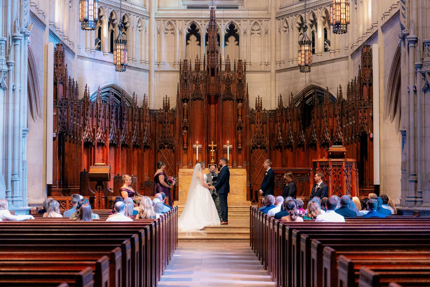 Bride and groom stand at the altar of a grand Gothic church during their wedding ceremony.