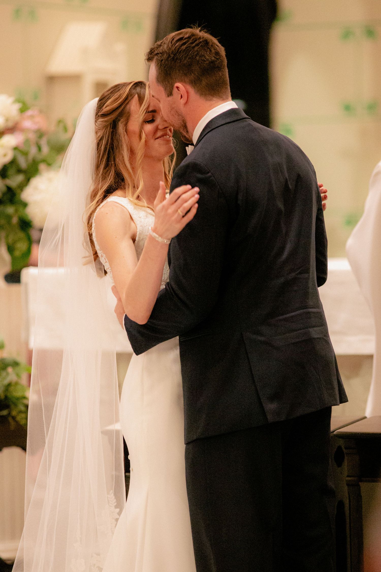 Bride and groom share their first kiss at the altar in a beautiful church wedding ceremony.