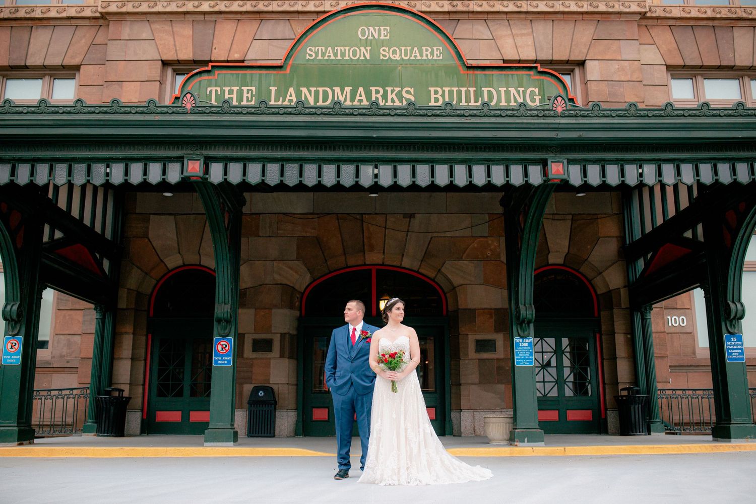 Bride and groom pose in front of The Landmarks Building at One Station Square on their wedding day.