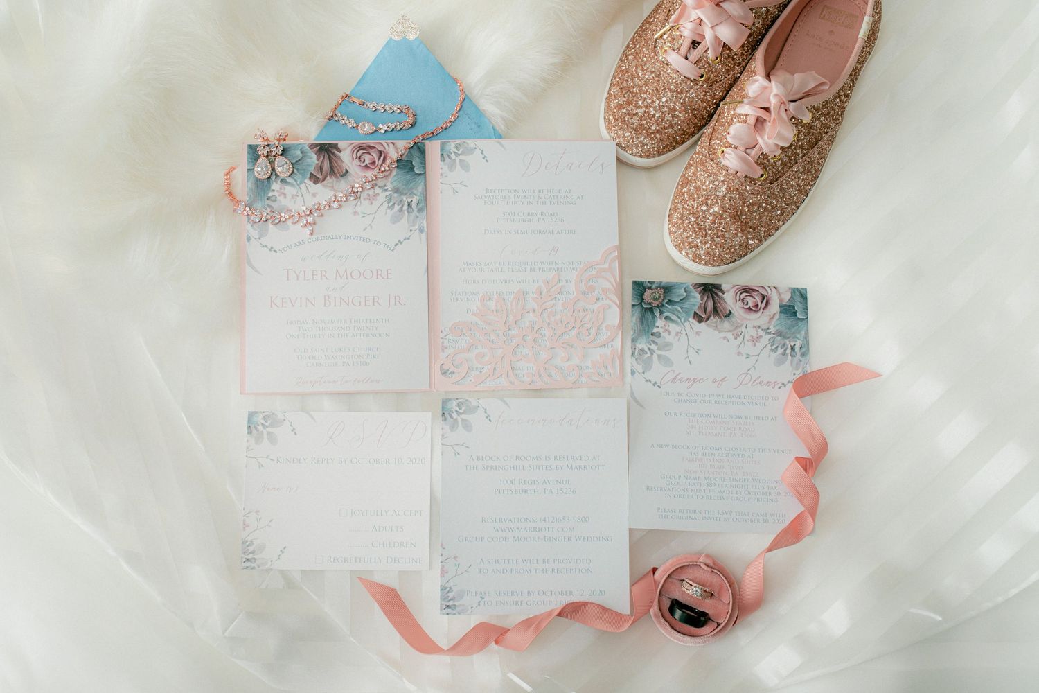 Flat lay of pink and blue wedding invitation suite with gold glitter sneakers and satin ribbon.