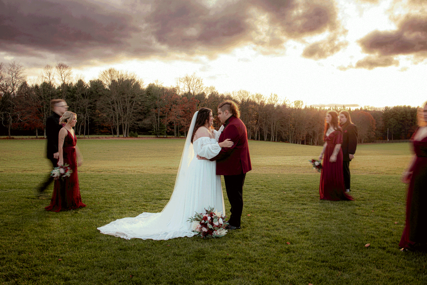 Gif of wedding party in slow motion walking around a bride and groom beneath a dramatic sunset sky.