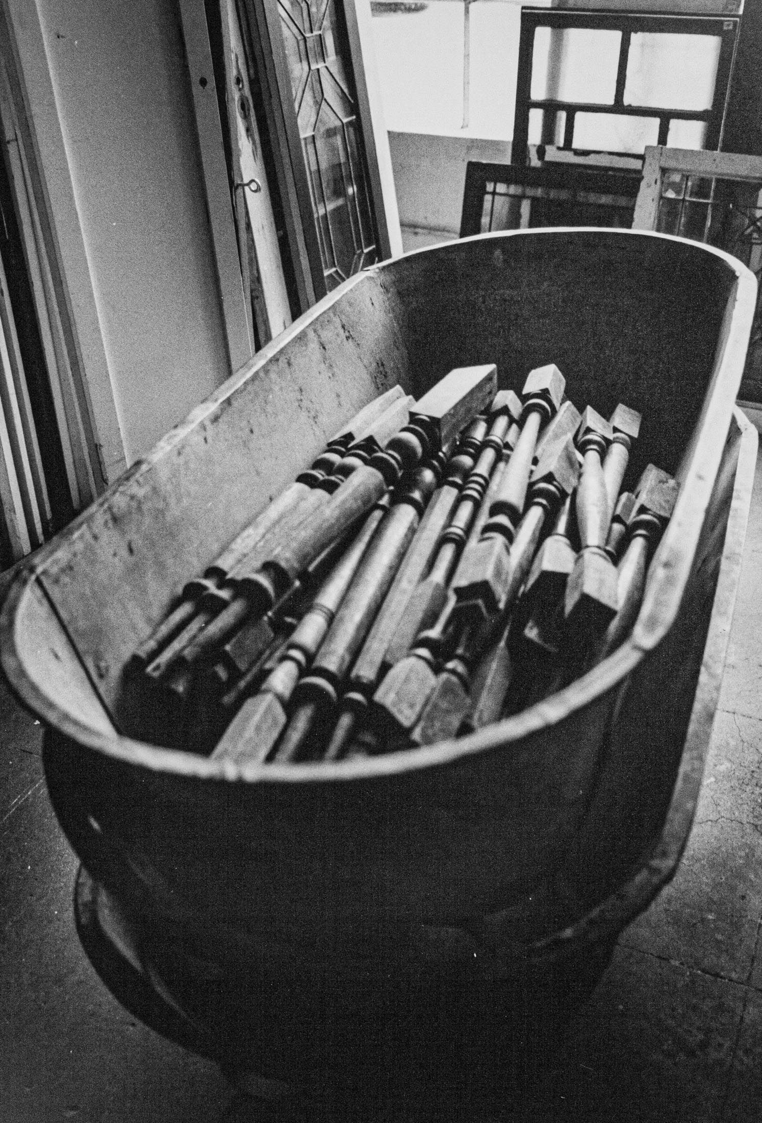 black and white silver gelatin print of oval bathtub containing table legs at Architectural Salvage, San DIego