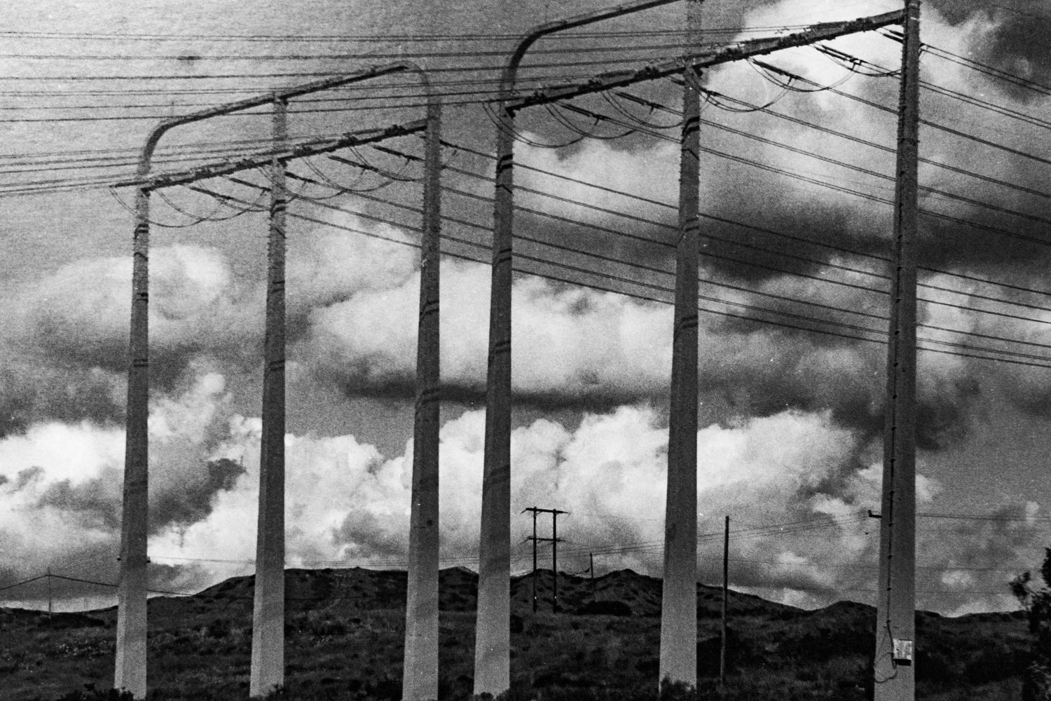 black and white silver gelatin print of power lines and towers shrouded by moody afternoon clouds, shot with red filter Camp Pendleton, CA