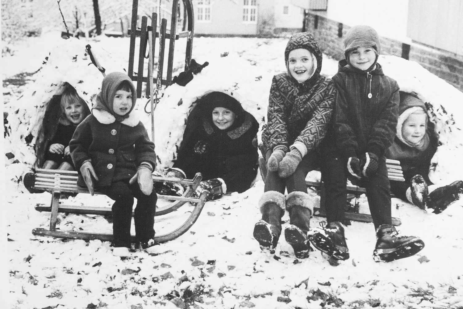 black and white silver gelatin print of joyous school children posing on and within their sculpted snow fort, Marburg, Germany