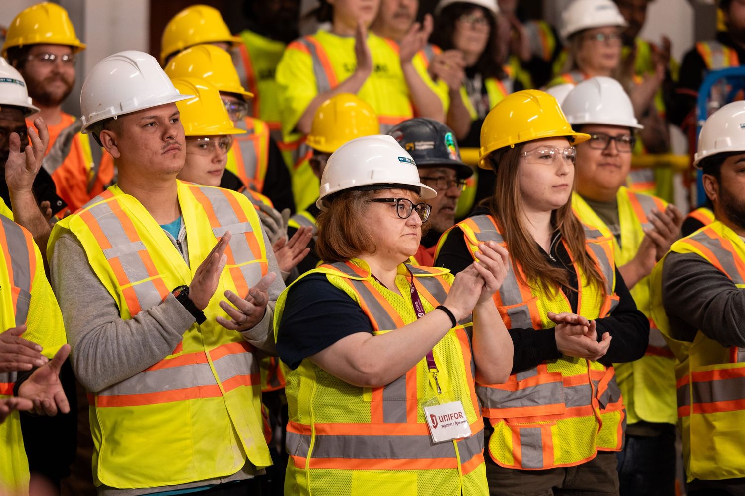 A group of construction workers applauds at an event for industrial construction documentary photography