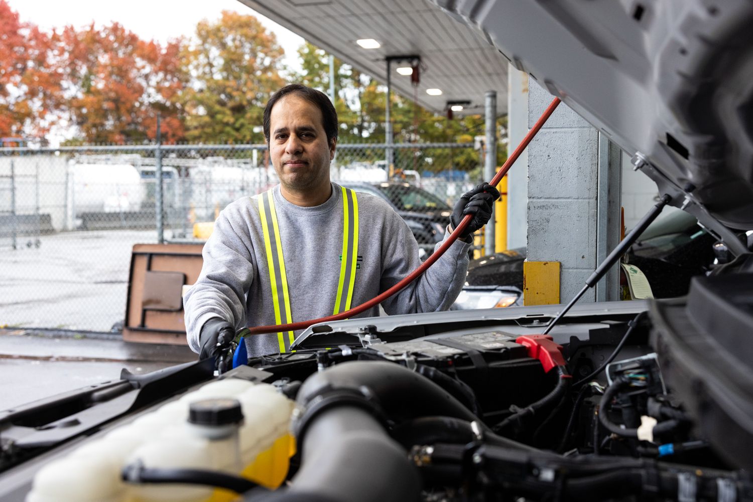 A mechanic works on a car in an airport for an industrial, construction, documentary photoshoot