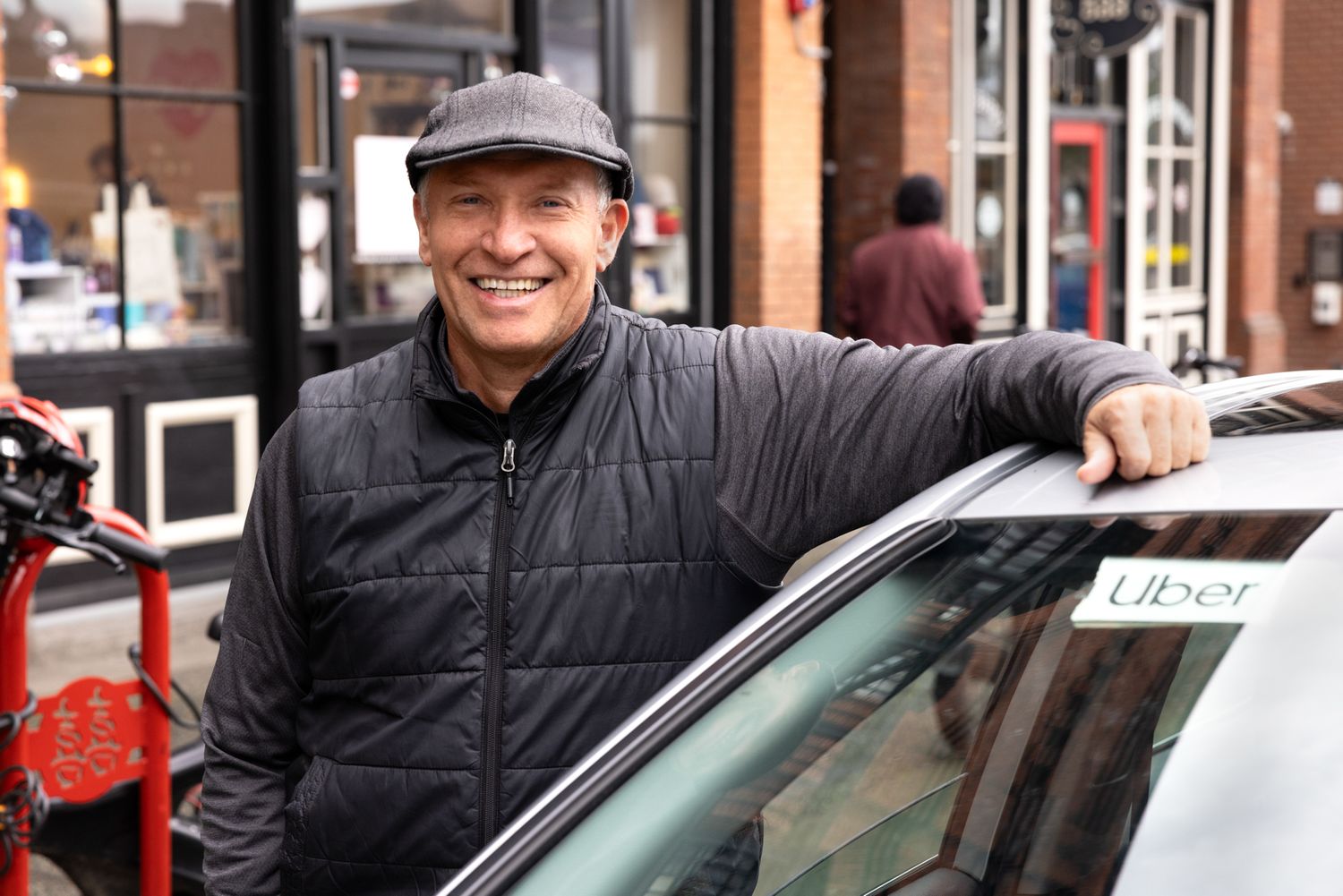 An immigrant Uber driver poses outside his car smiling. Unions, tech, gig economy, Commercial lifestyle photography.
