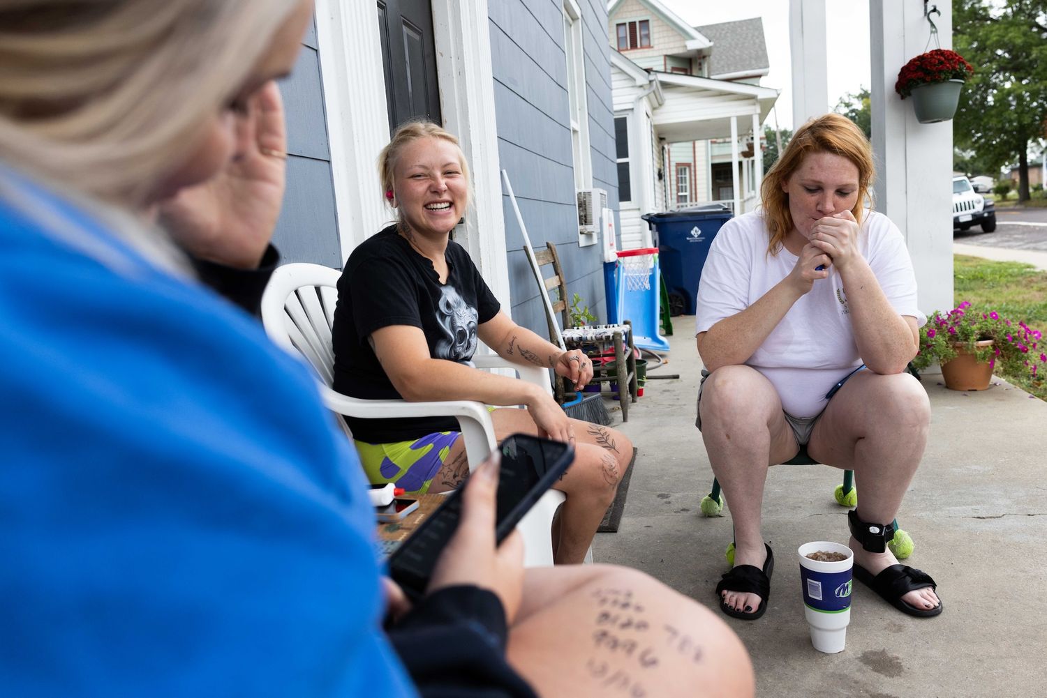 A group of women who are recovering addicts sit on the porch laughing, a documentary photography project