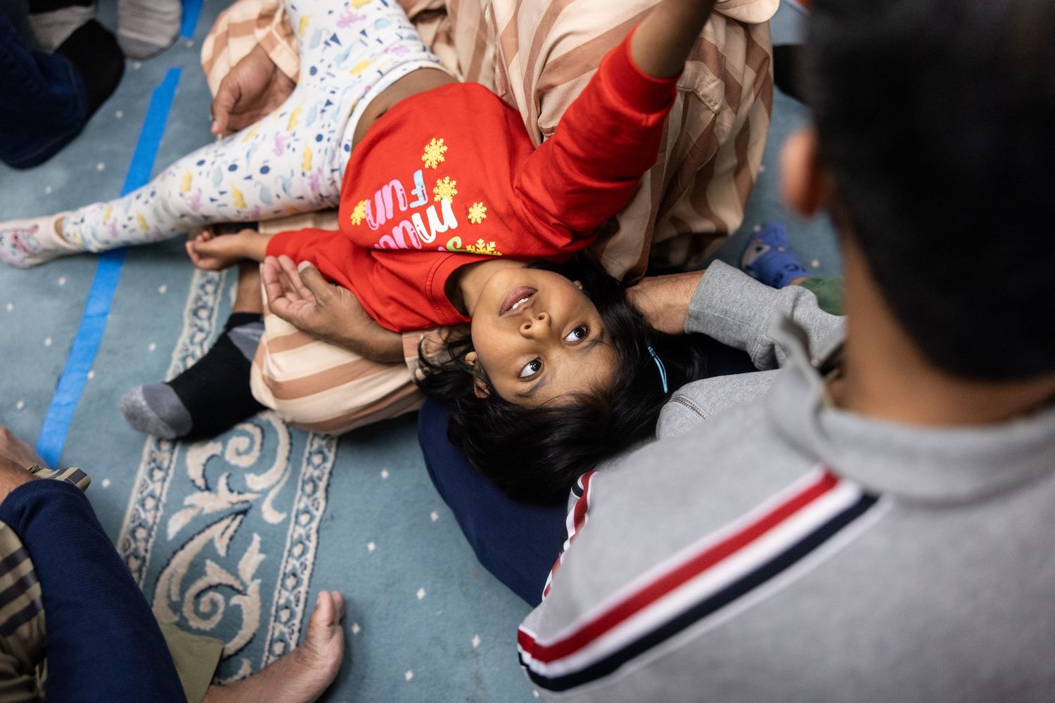 A young girl reaches for her parents at a mosque