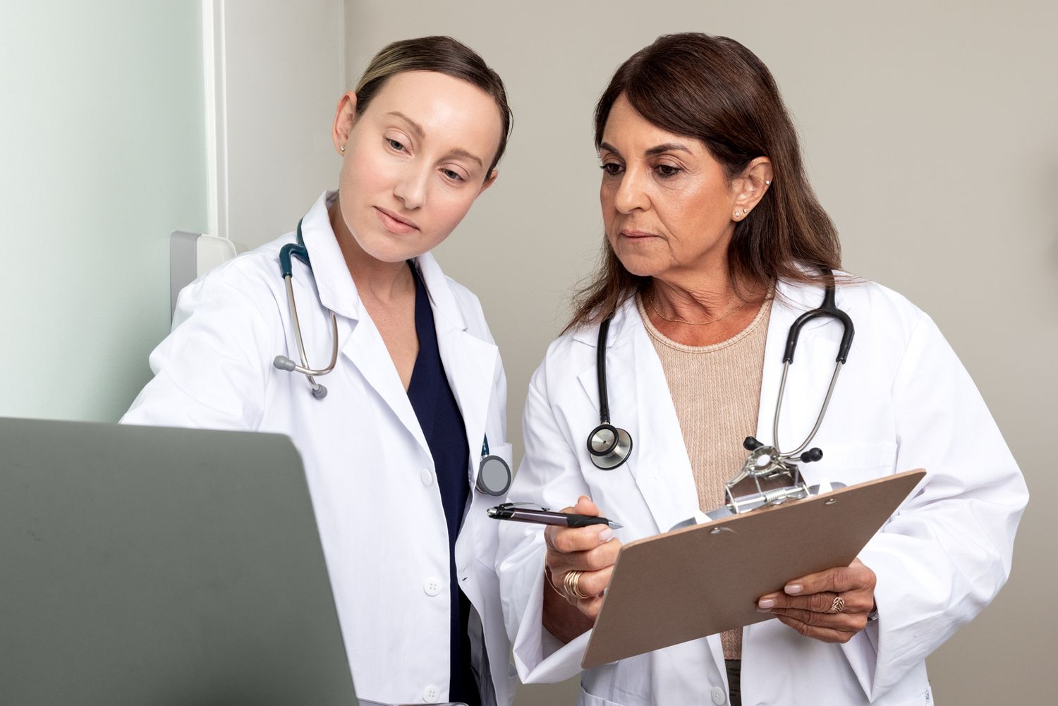 Two doctors examine a patient chart. Commercial lifestyle photography, medical, family, doctors, industry.