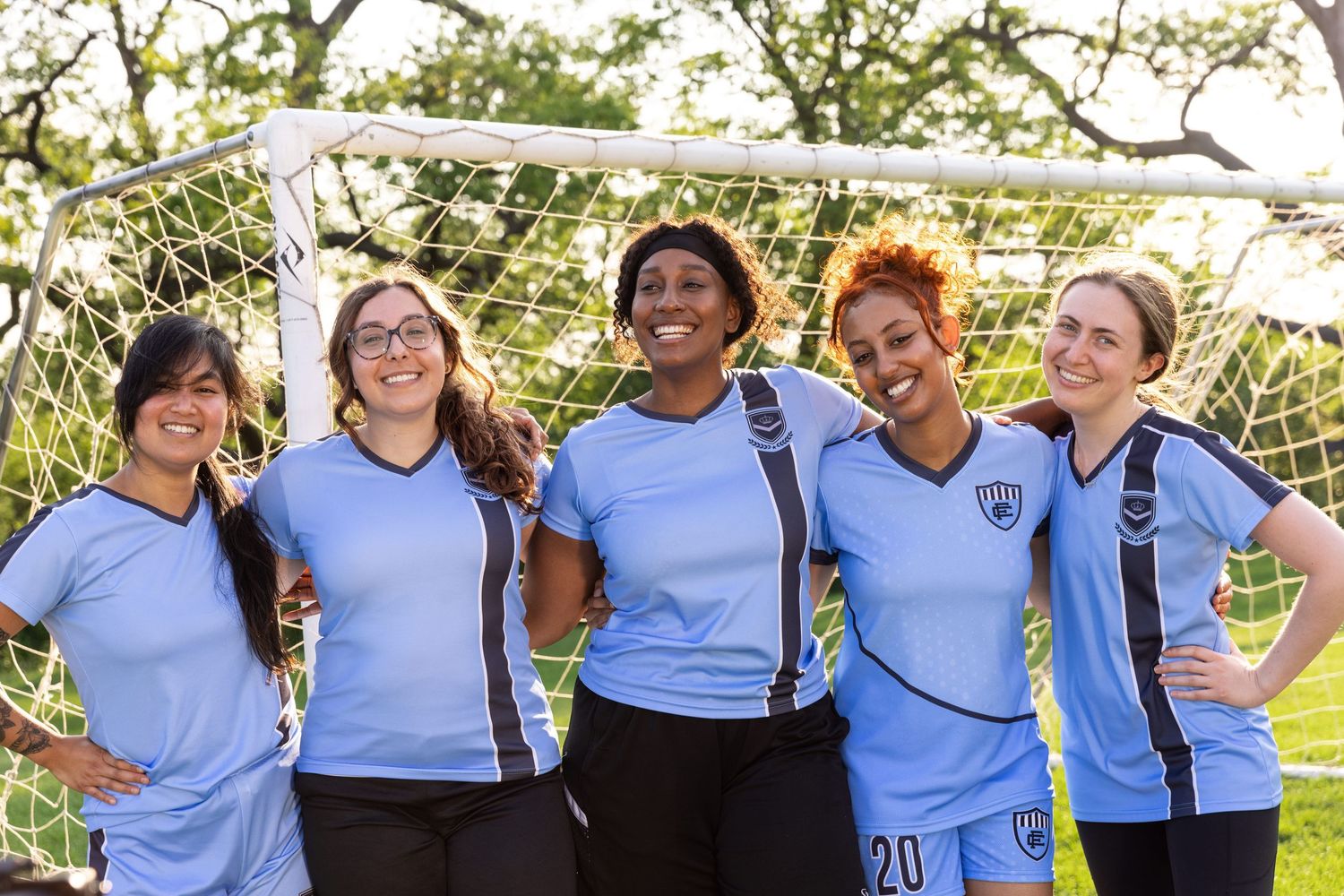 A group of diverse women smiles while playing soccer. Commercial lifestyle photography, sports.