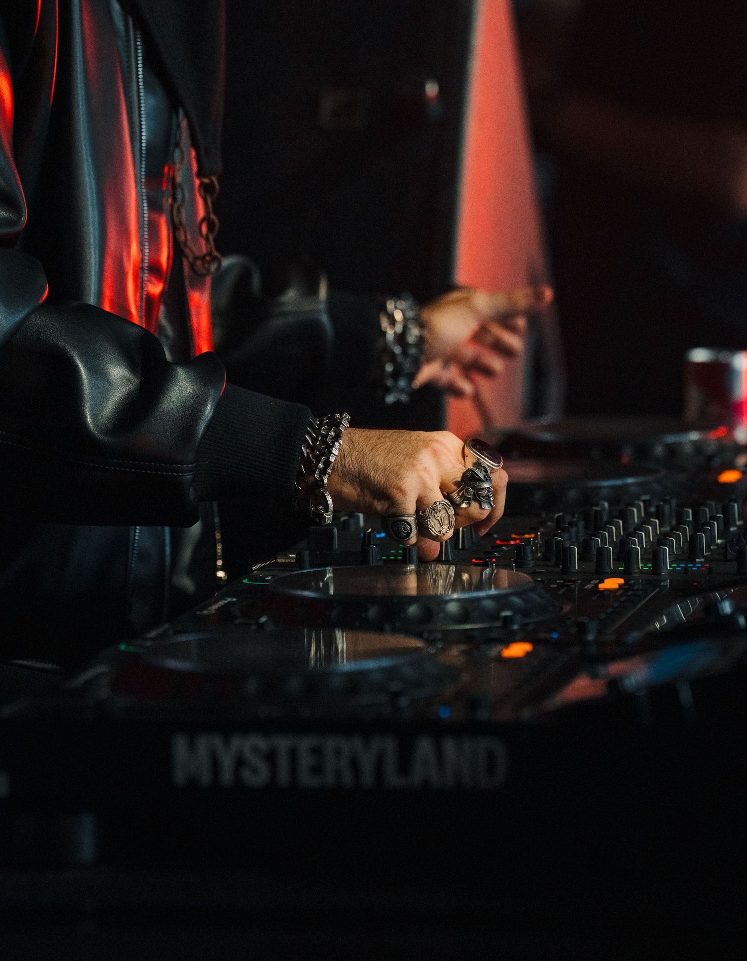 DJ performing at Mysteryland festival, hands on mixer with rings and bracelets under dark moody lighting.