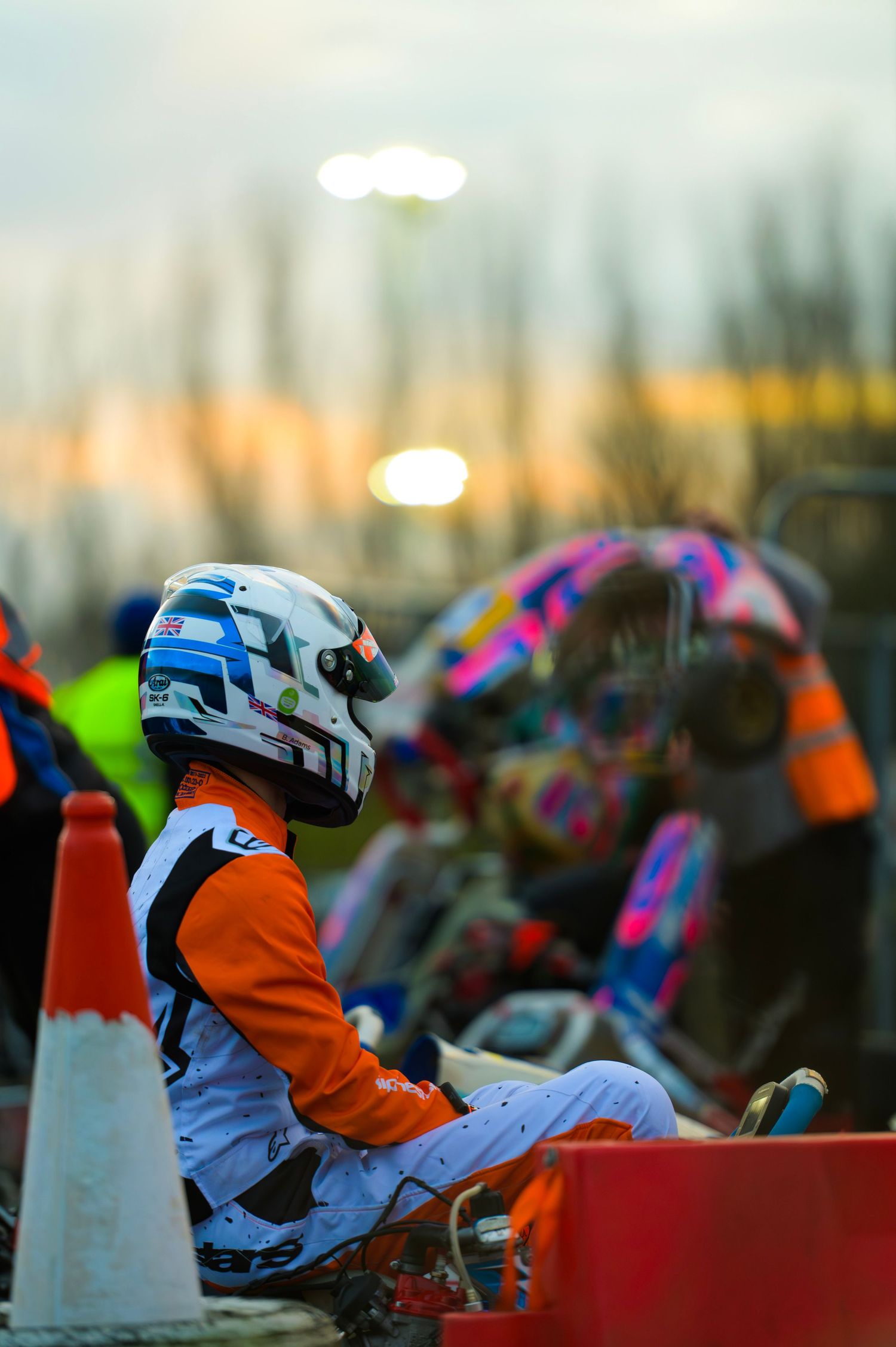 Row of go-kart racers in helmets lined up at sunset waiting to start.
