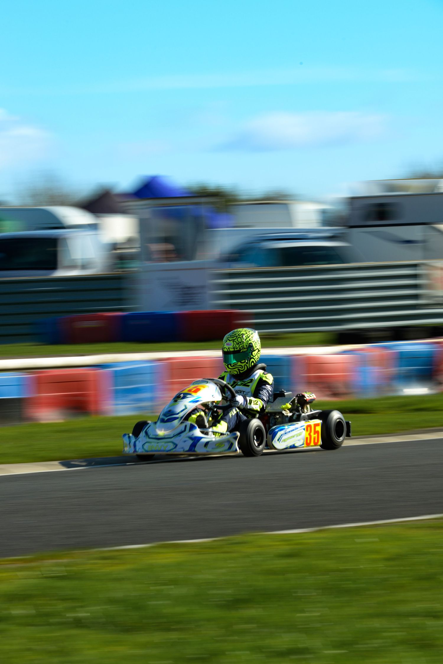 Go-kart racing action on an outdoor track with multiple karts competing at high speeds.