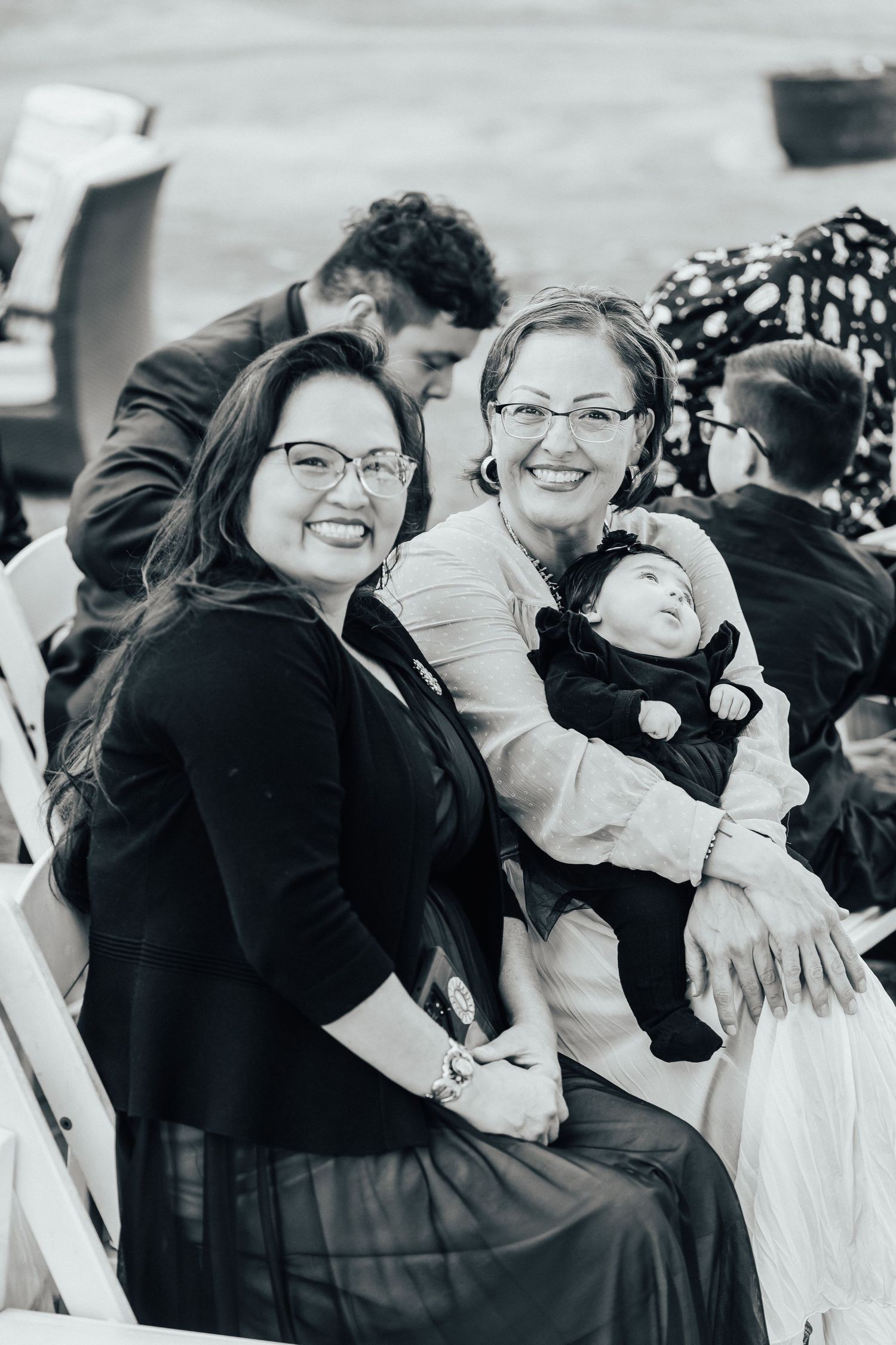 Black and white portrait of three generations enjoying a happy moment together at a gathering.
